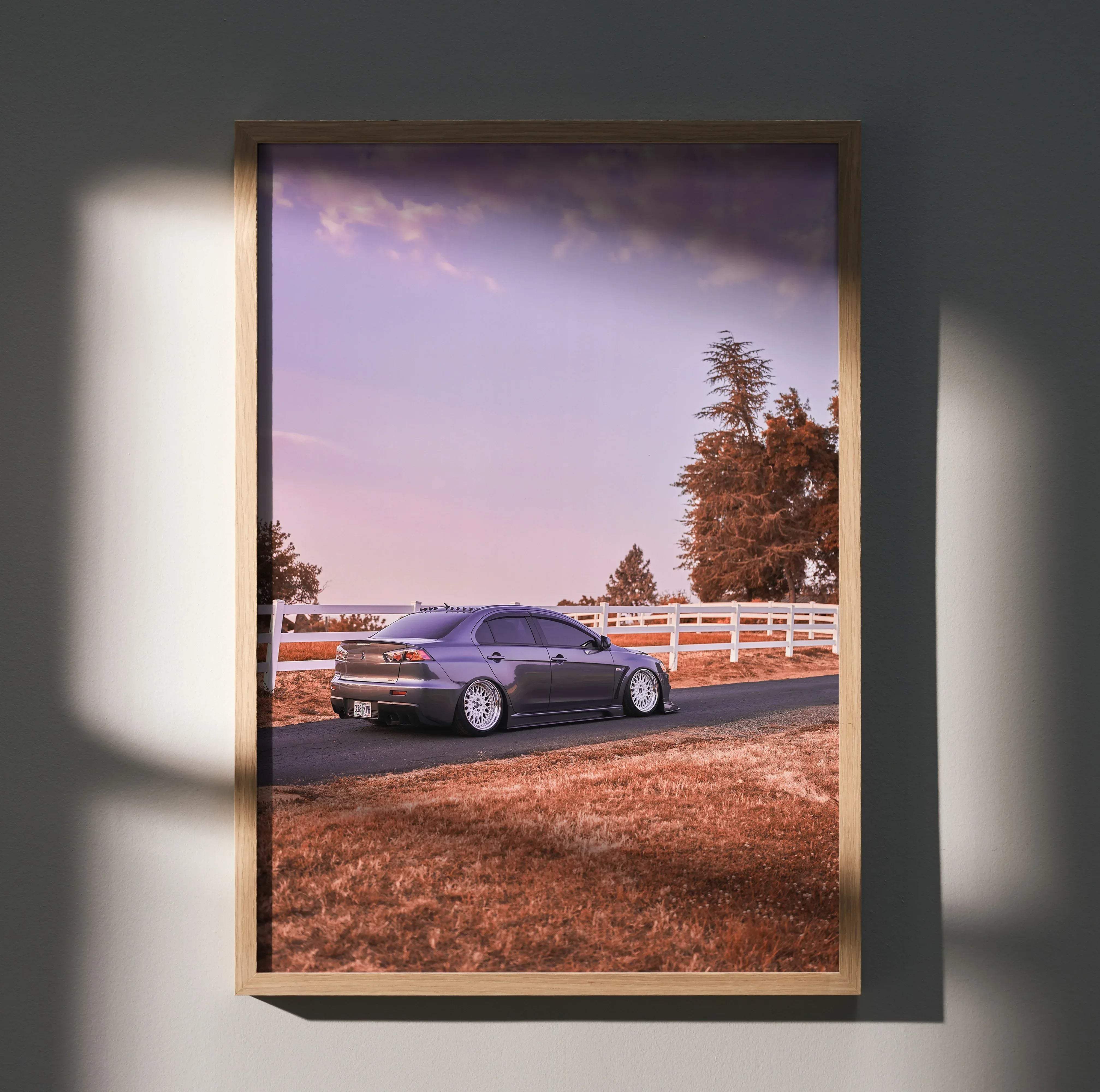 A framed high resolution poster of a dark gray mitsubishi lancer evolution sedan parked on a rural road at twilight
