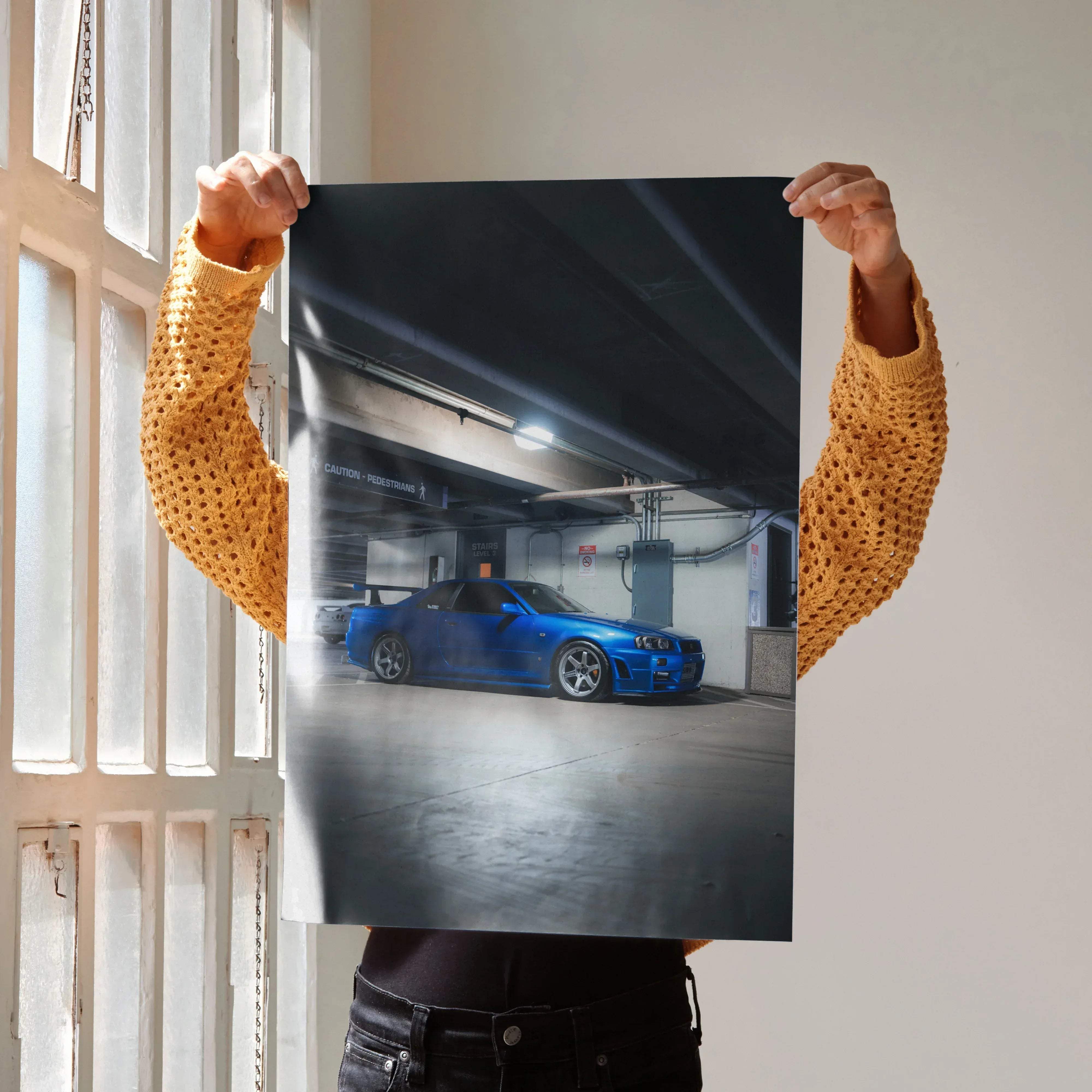 Vibrant blue Nissan R34 GTR Skyline high resolution car poster with glossy finish and dynamic lighting in garage setting