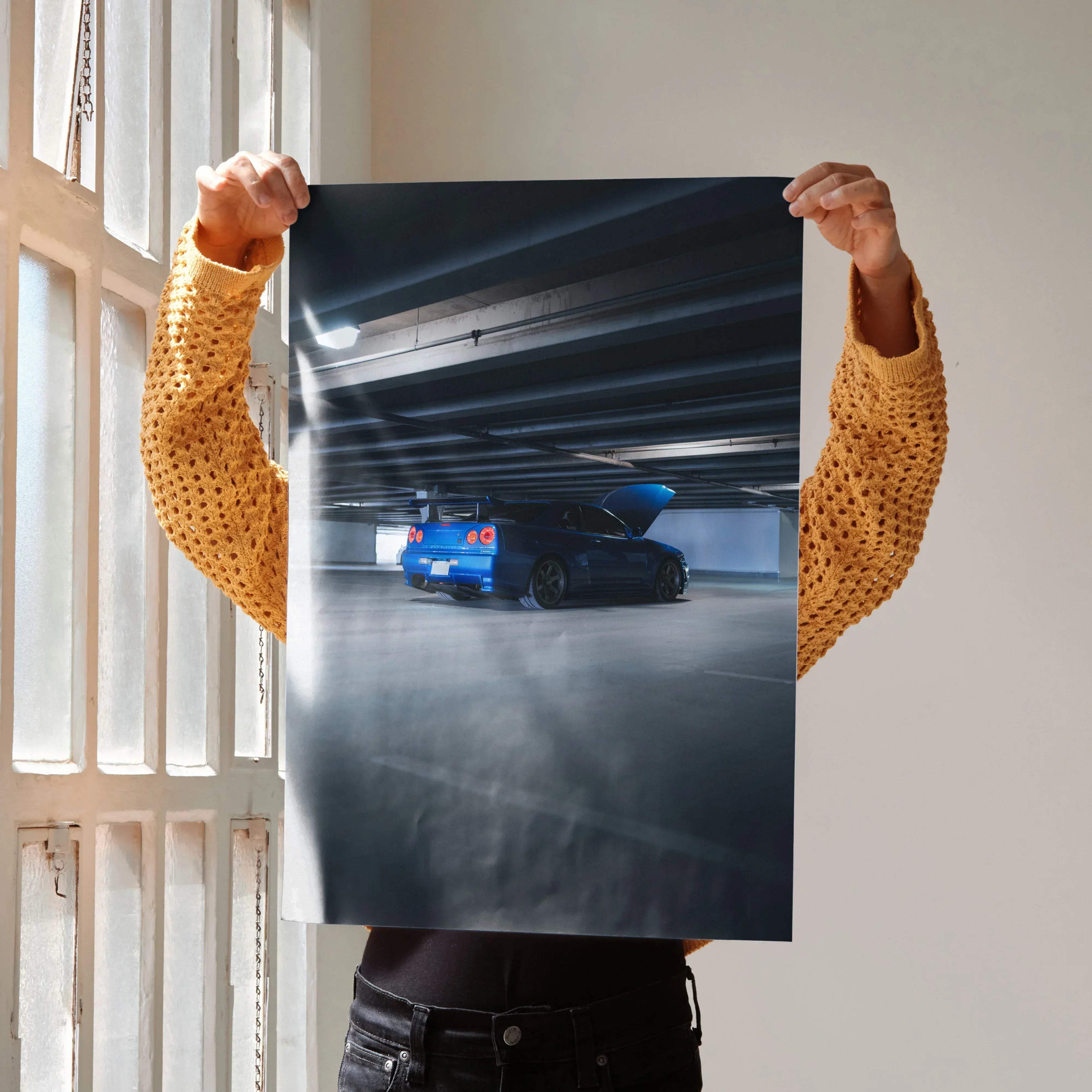 Blue Nissan R34 GTR Skyline sports car poster with hood open in dimly lit underground garage setting