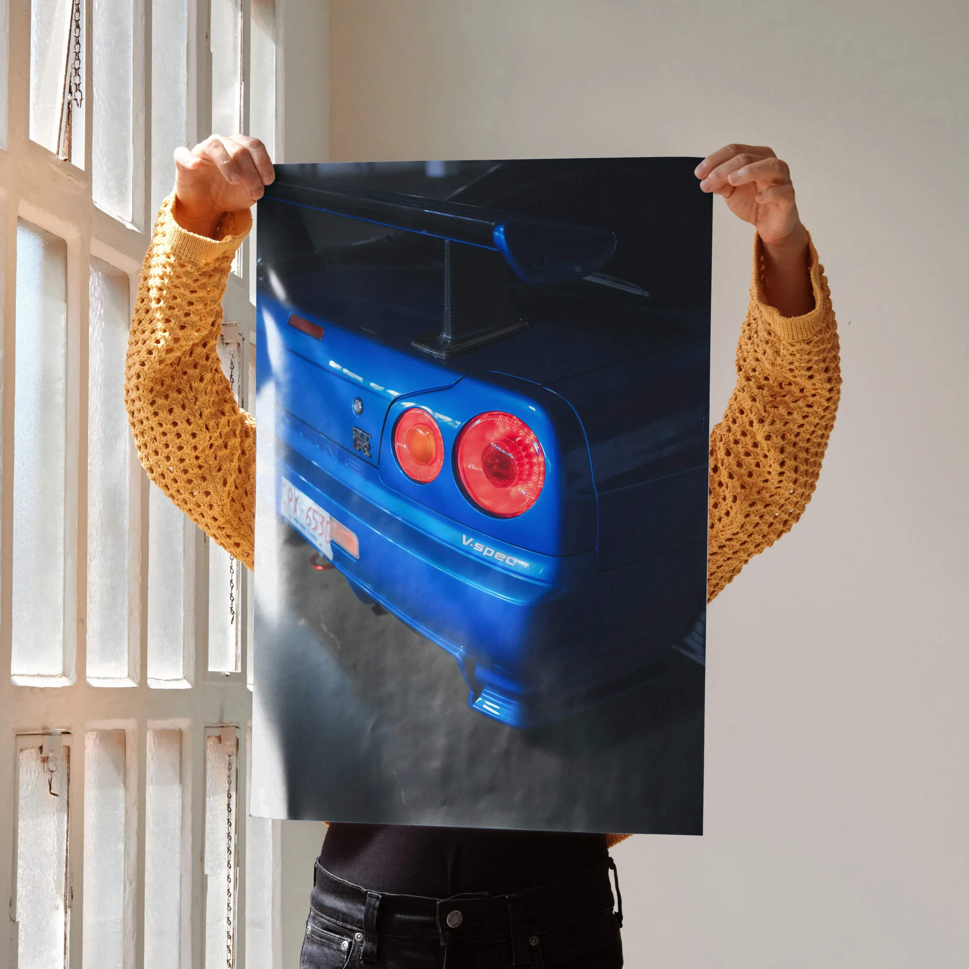 Rear view of vibrant blue Nissan R34 GTR Skyline car poster with glowing red taillights and prominent rear spoiler