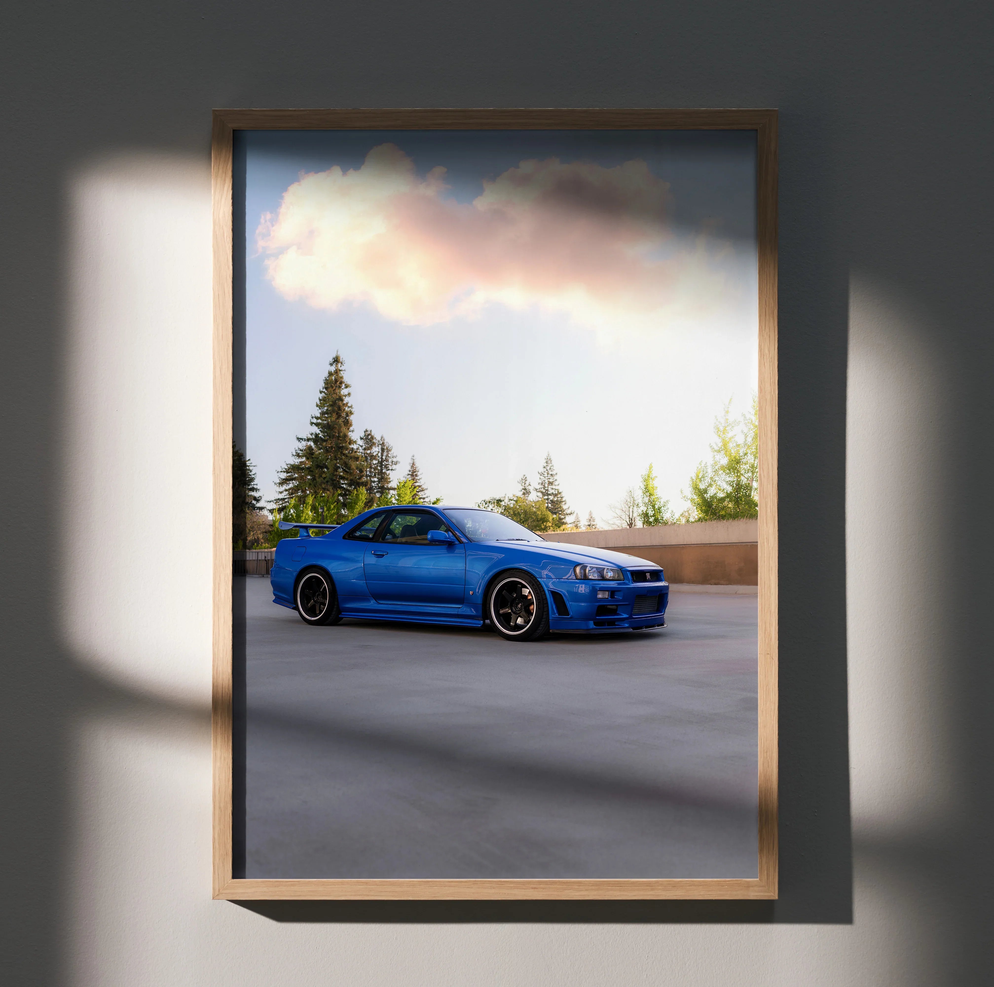 Nissan R34 GTR in blue parked outdoors with trees and clouds background Poster Wall Art.