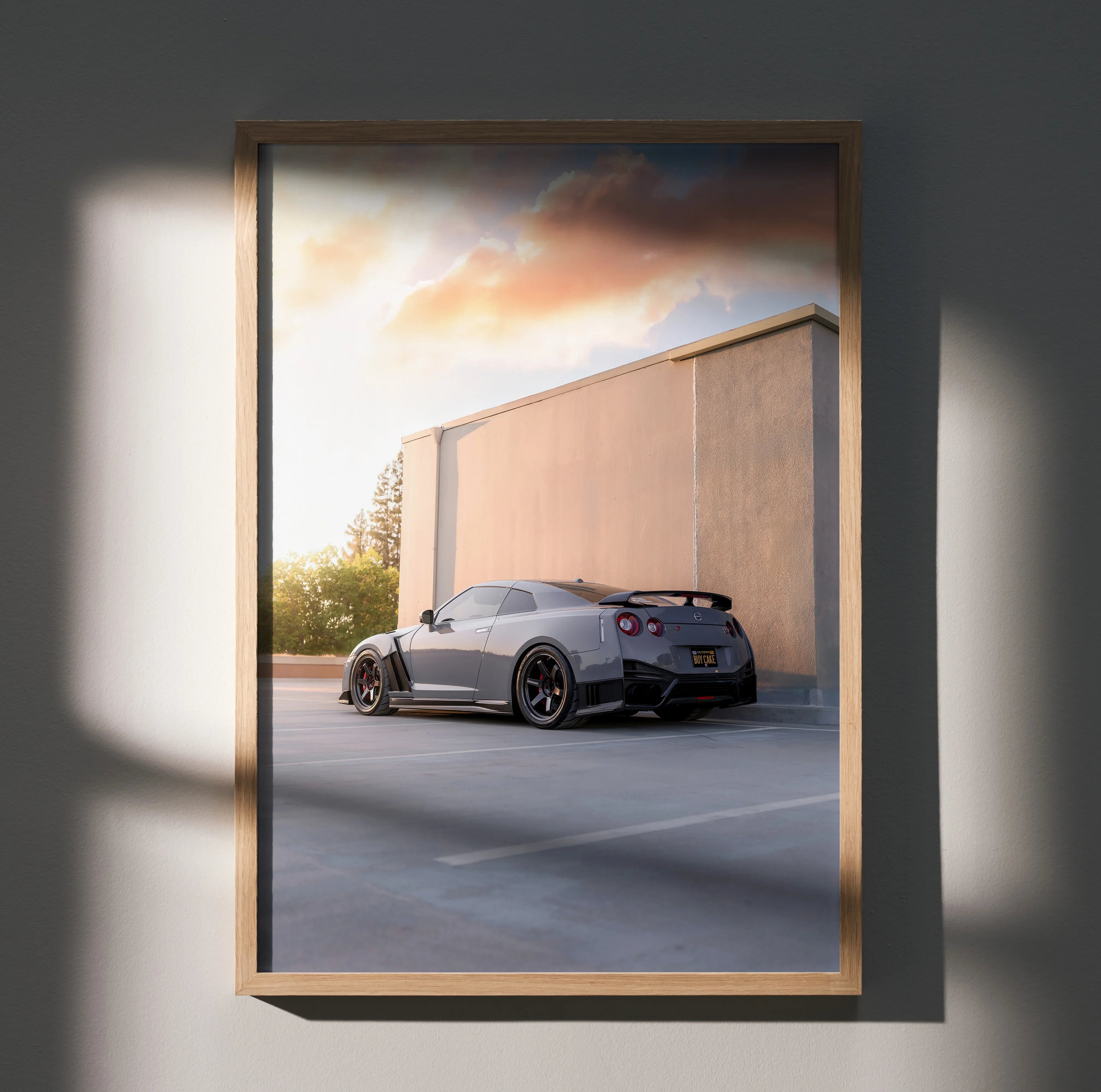 Nissan GTR R35 parked by concrete wall at sunset poster wall art with warm lighting.