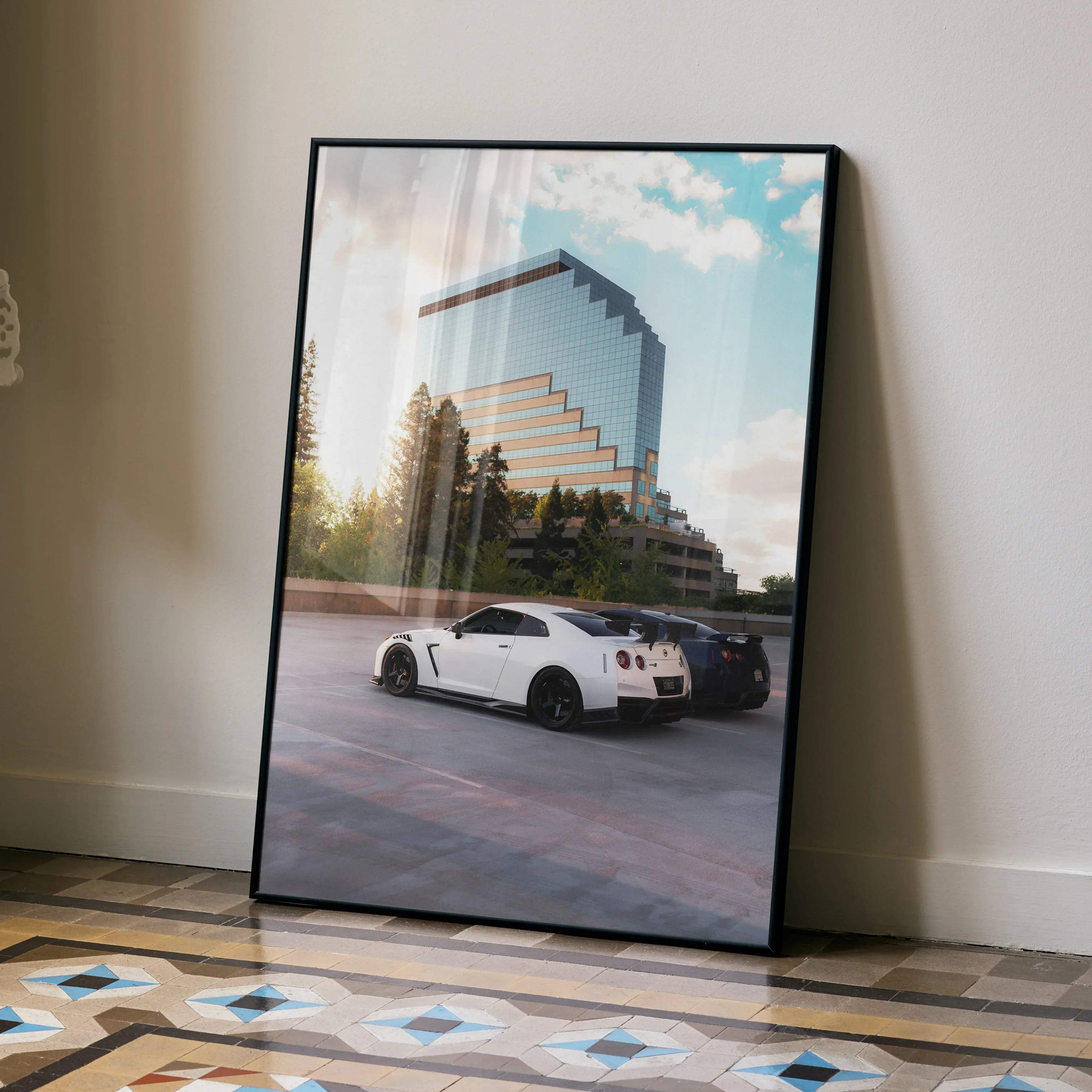Black-framed Nissan GTR R35 high resolution poster featuring a white Nissan GT-R and dark sports car by glass building