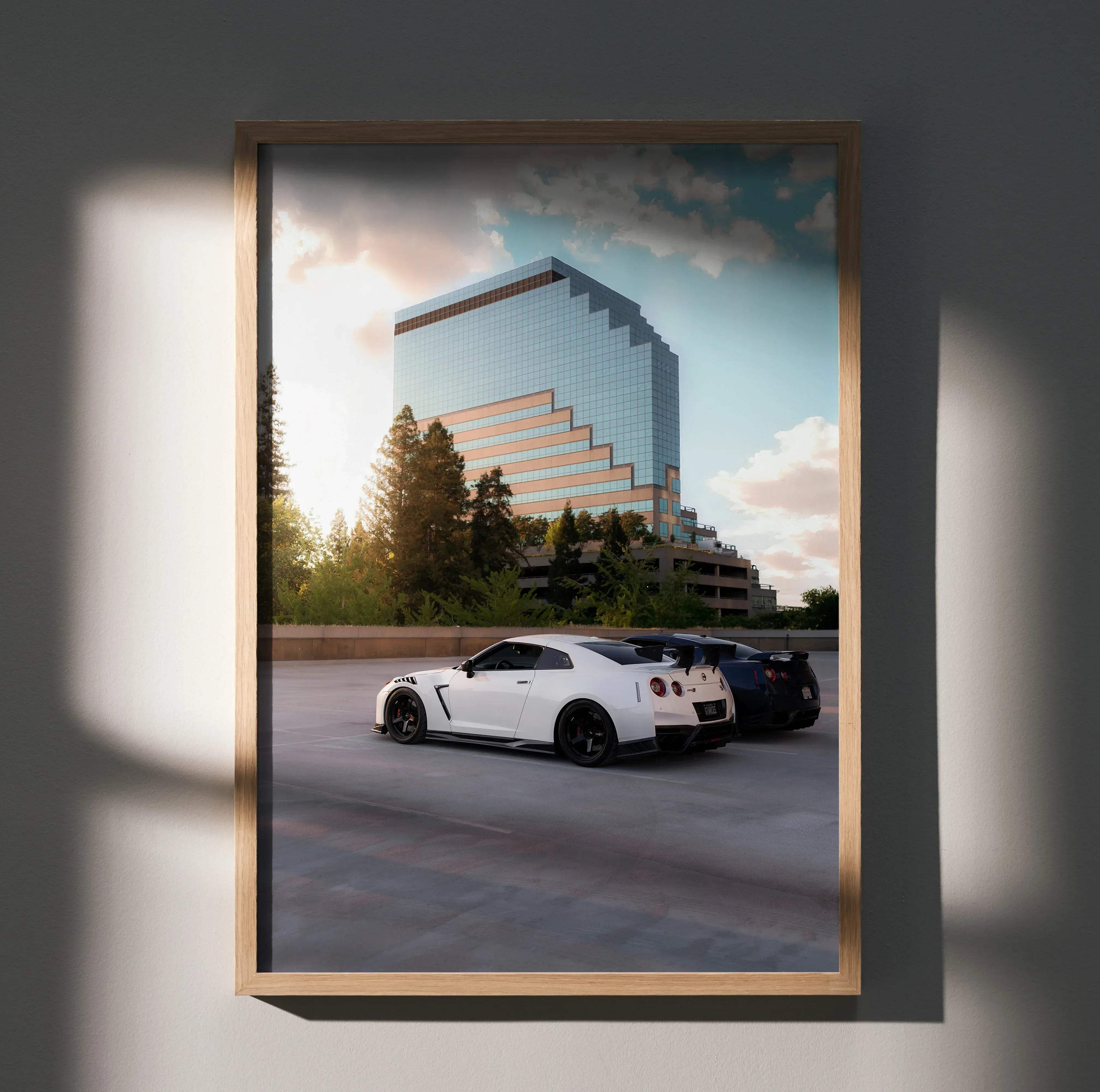 A framed high resolution poster of a white nissan gt-r r35 sports car parked in front of a modern glass building