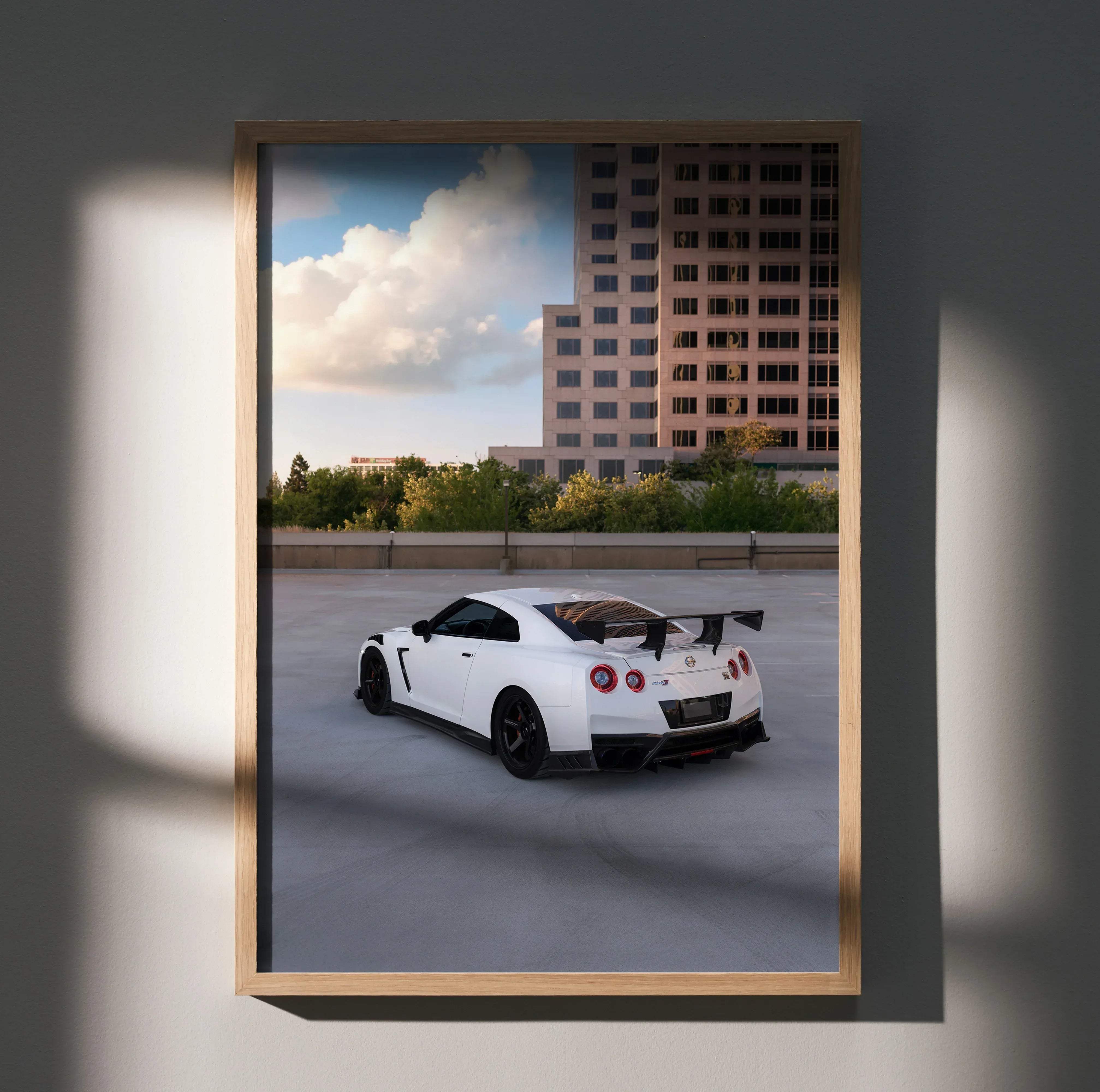 White Nissan GT-R R35 sports car with black rims and rear spoiler framed in light wood high resolution car poster