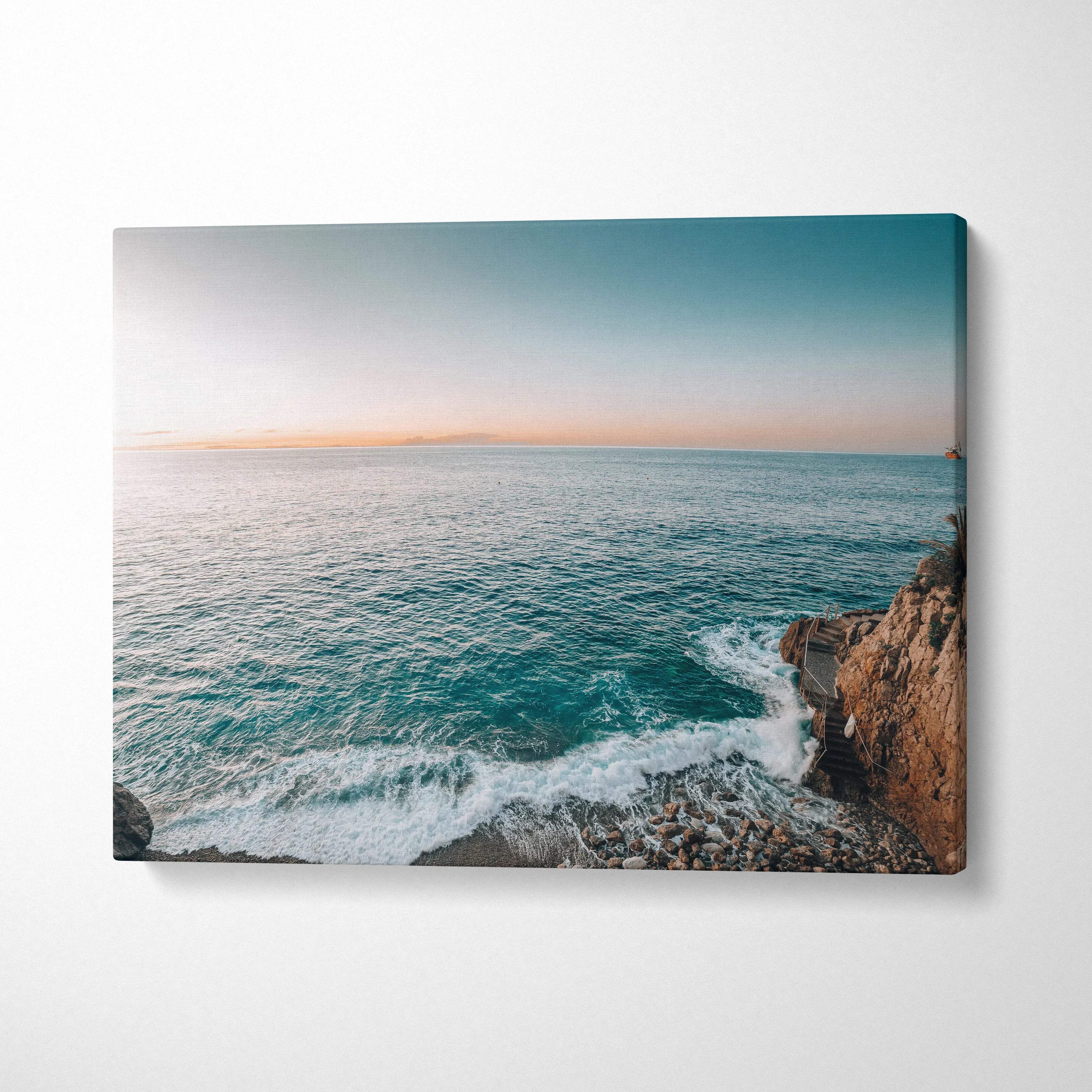 Coastal canvas wall art of turquoise waves crashing on rocky cliffs at sunset