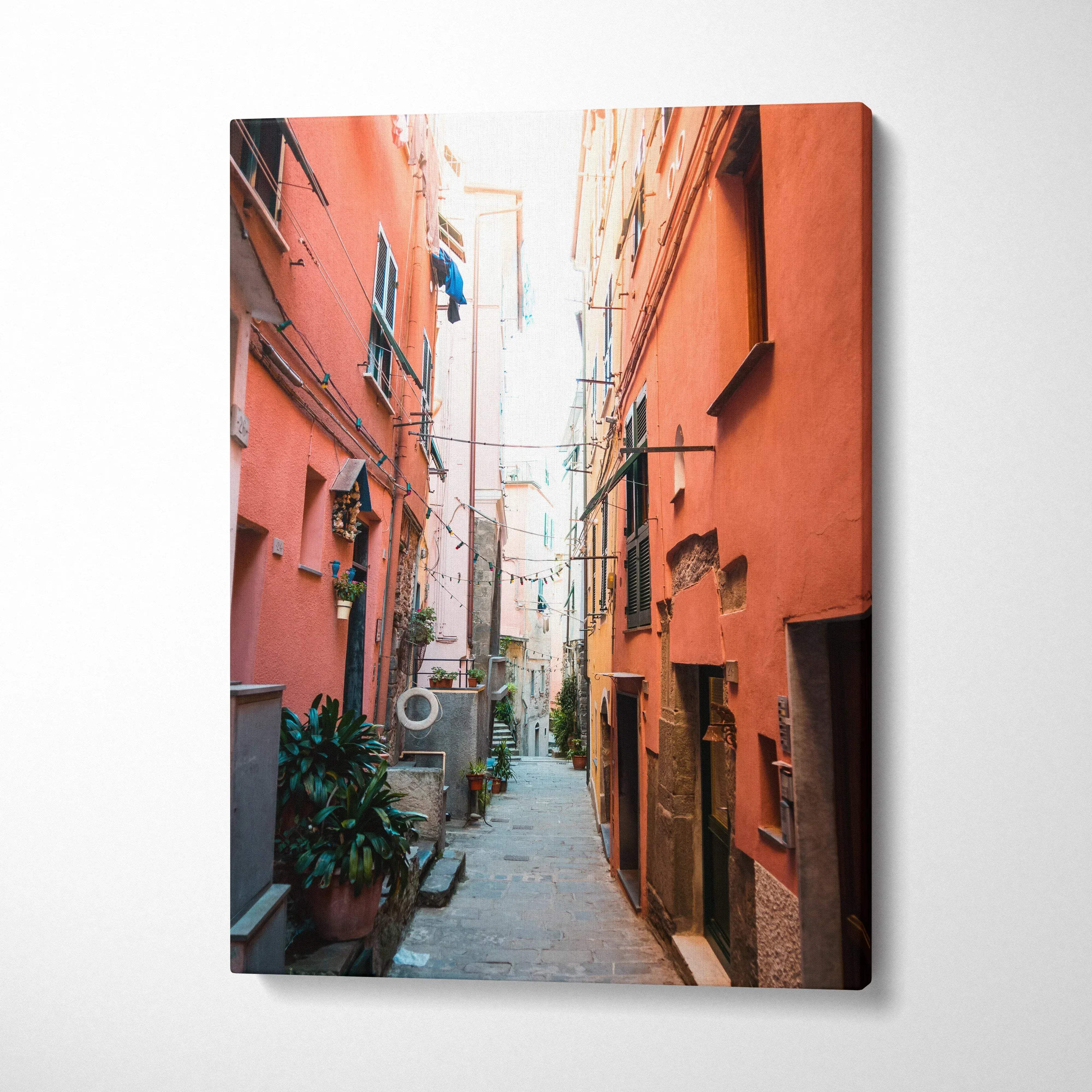 Vertical canvas wall art of a narrow alley with orange buildings and vibrant architectural details.