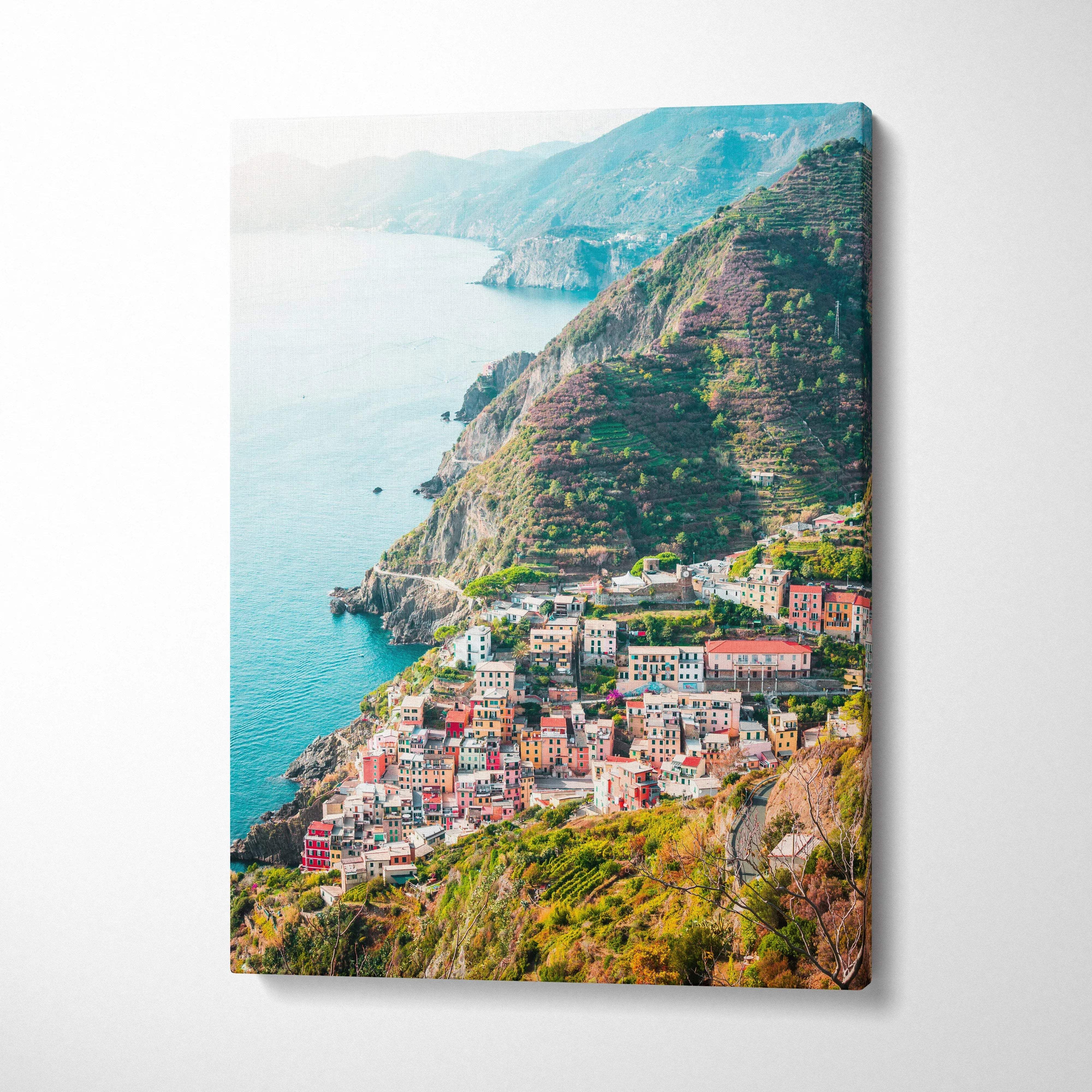 Canvas wall art featuring vibrant coastal architecture and lush green cliffs over the ocean.