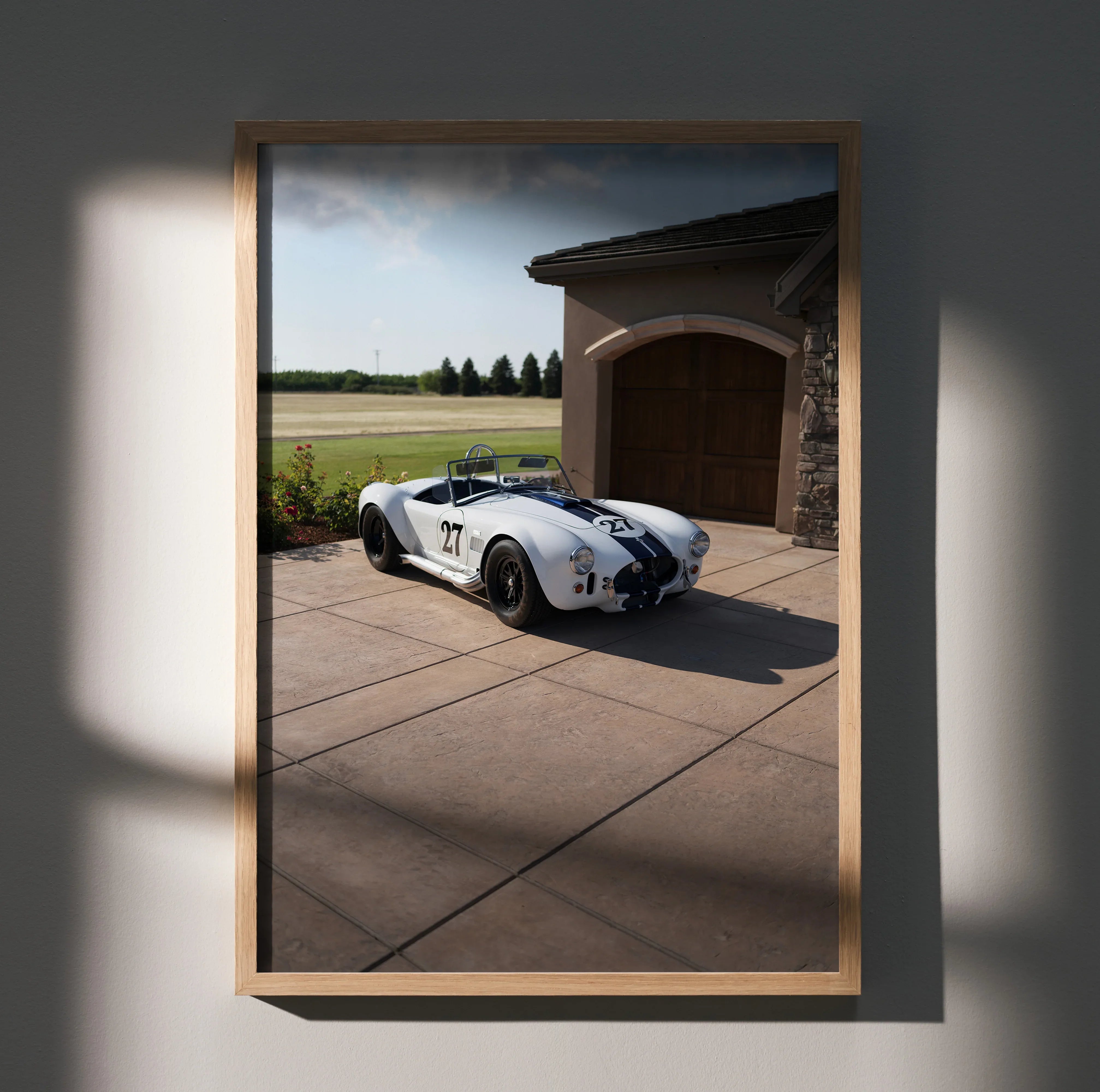 Shelby Cobra sports car with blue racing stripes parked by garage, high-resolution poster wall art.