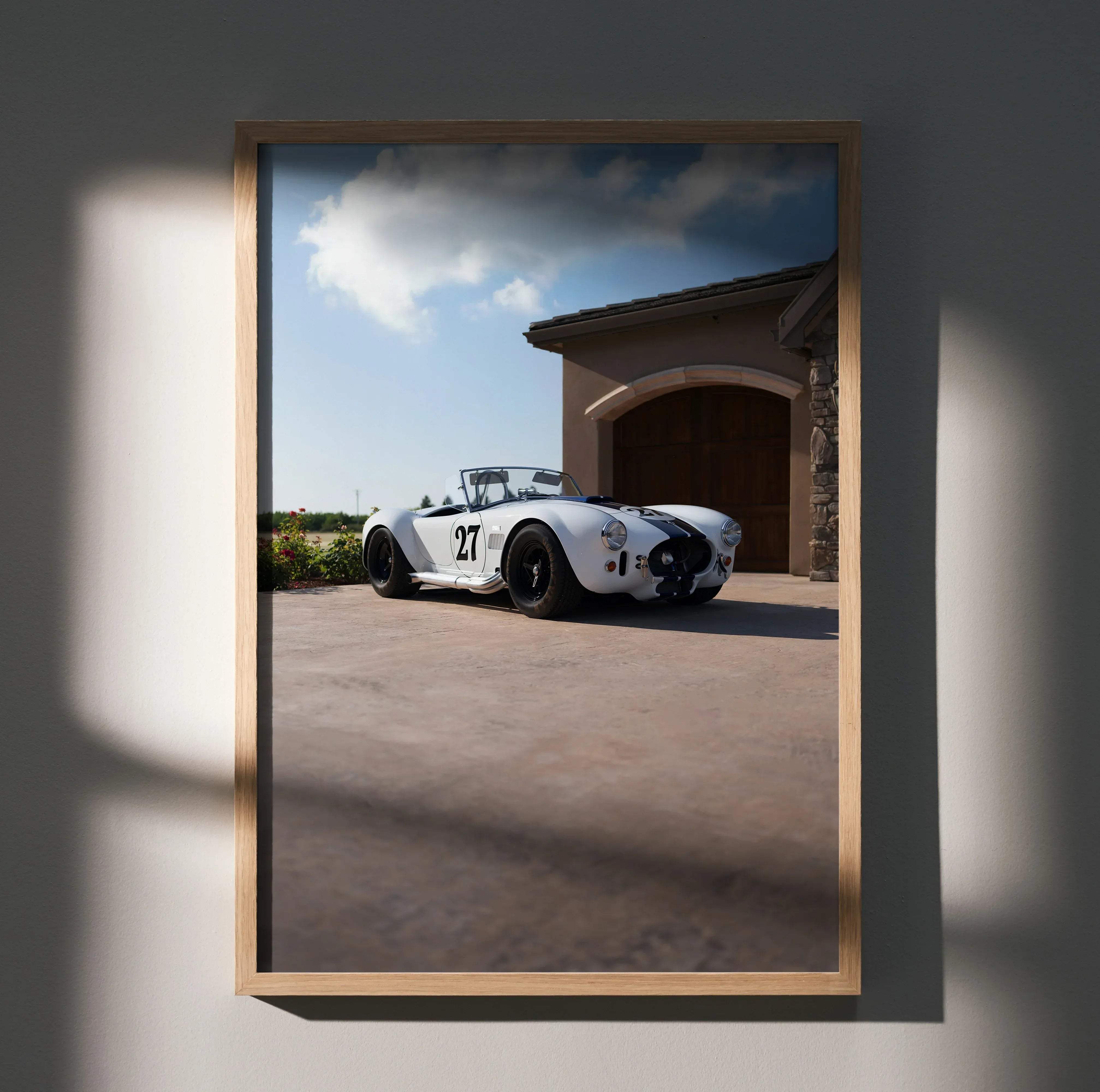 A framed shelby cobra high resolution car poster featuring a white and black racing car number 27 in a light wood frame
