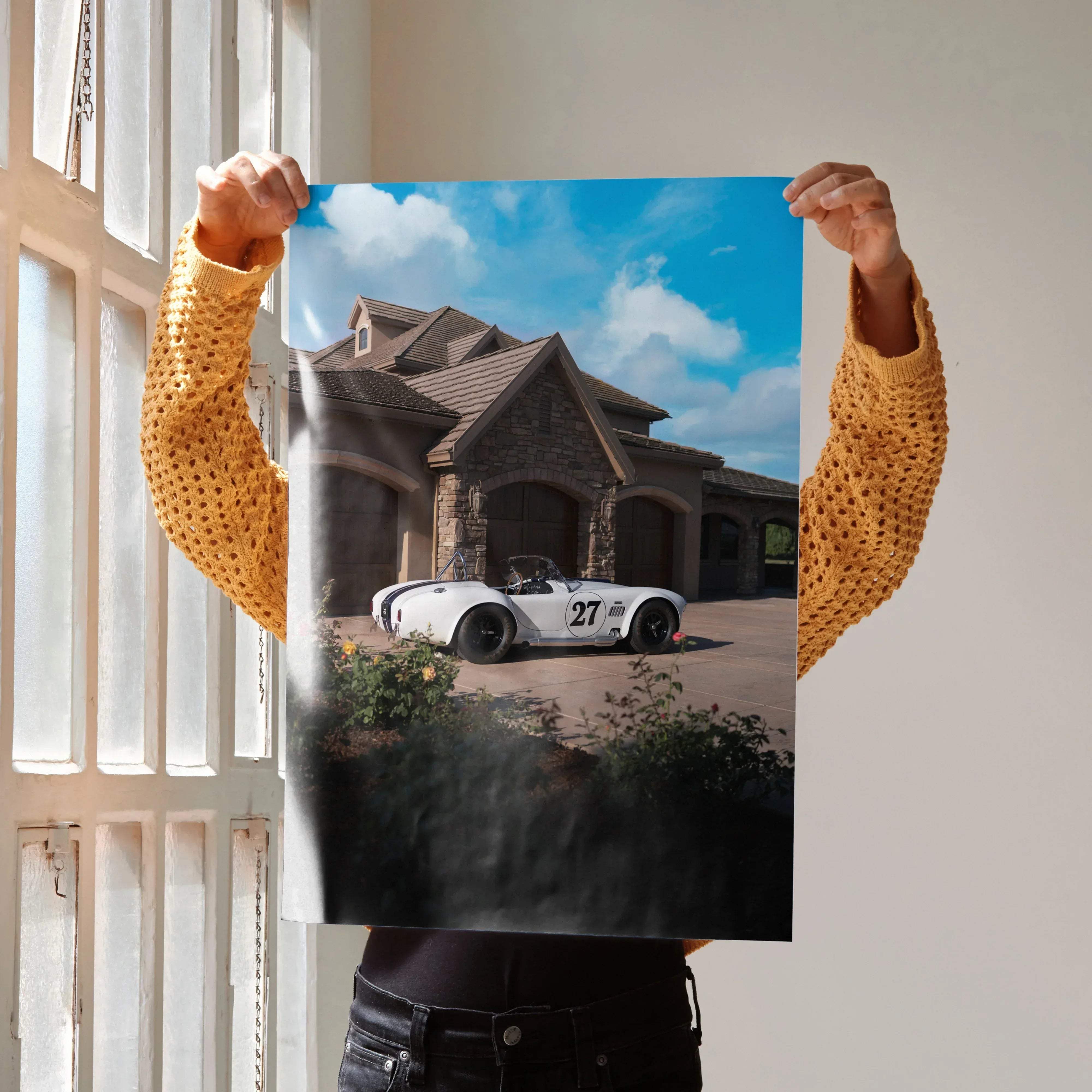 White Shelby Cobra sports car with black racing stripes and number 27 parked in front of a stone mansion poster
