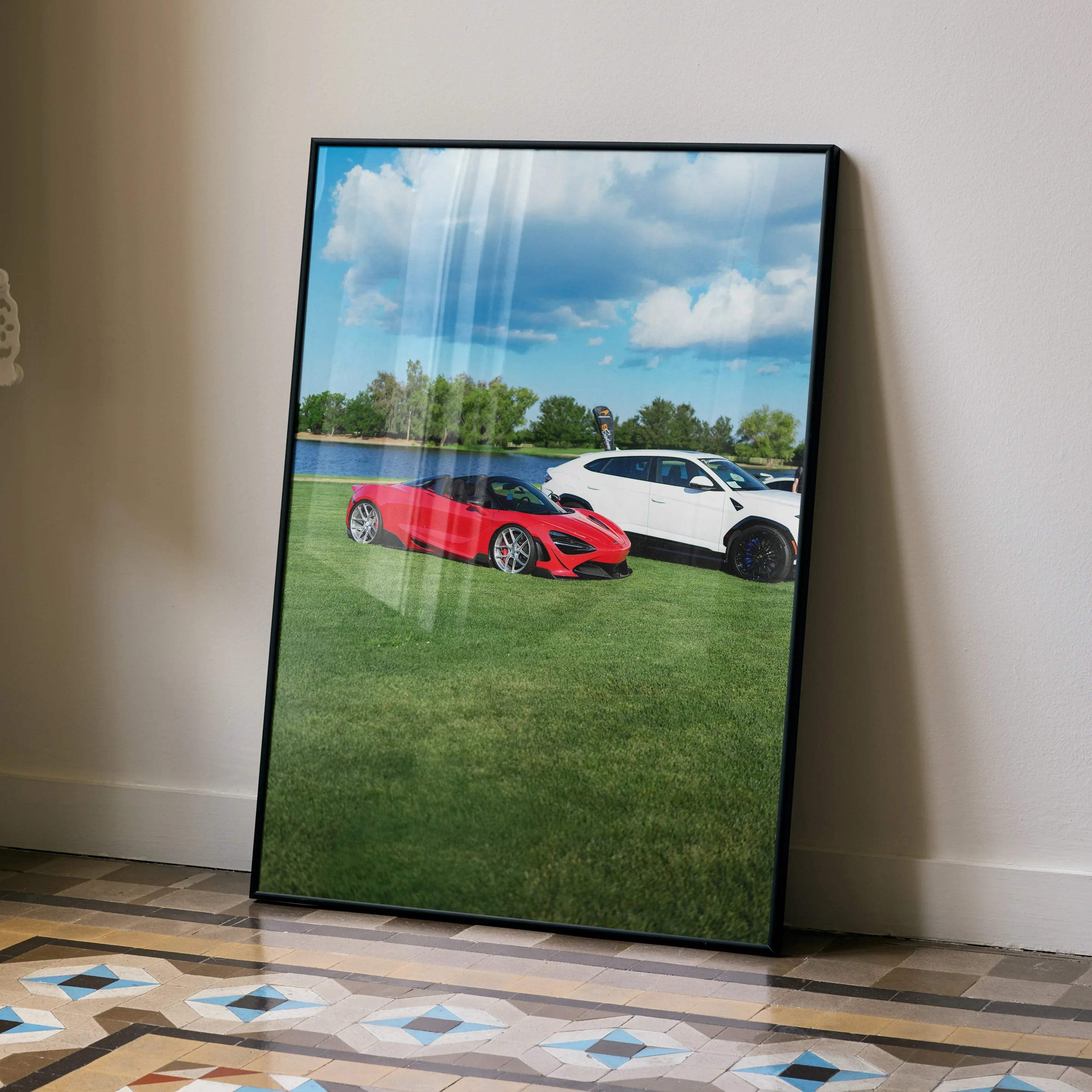 Black-framed McLaren 720S high resolution car poster featuring vibrant red McLaren and white SUV on green grass under blue sky
