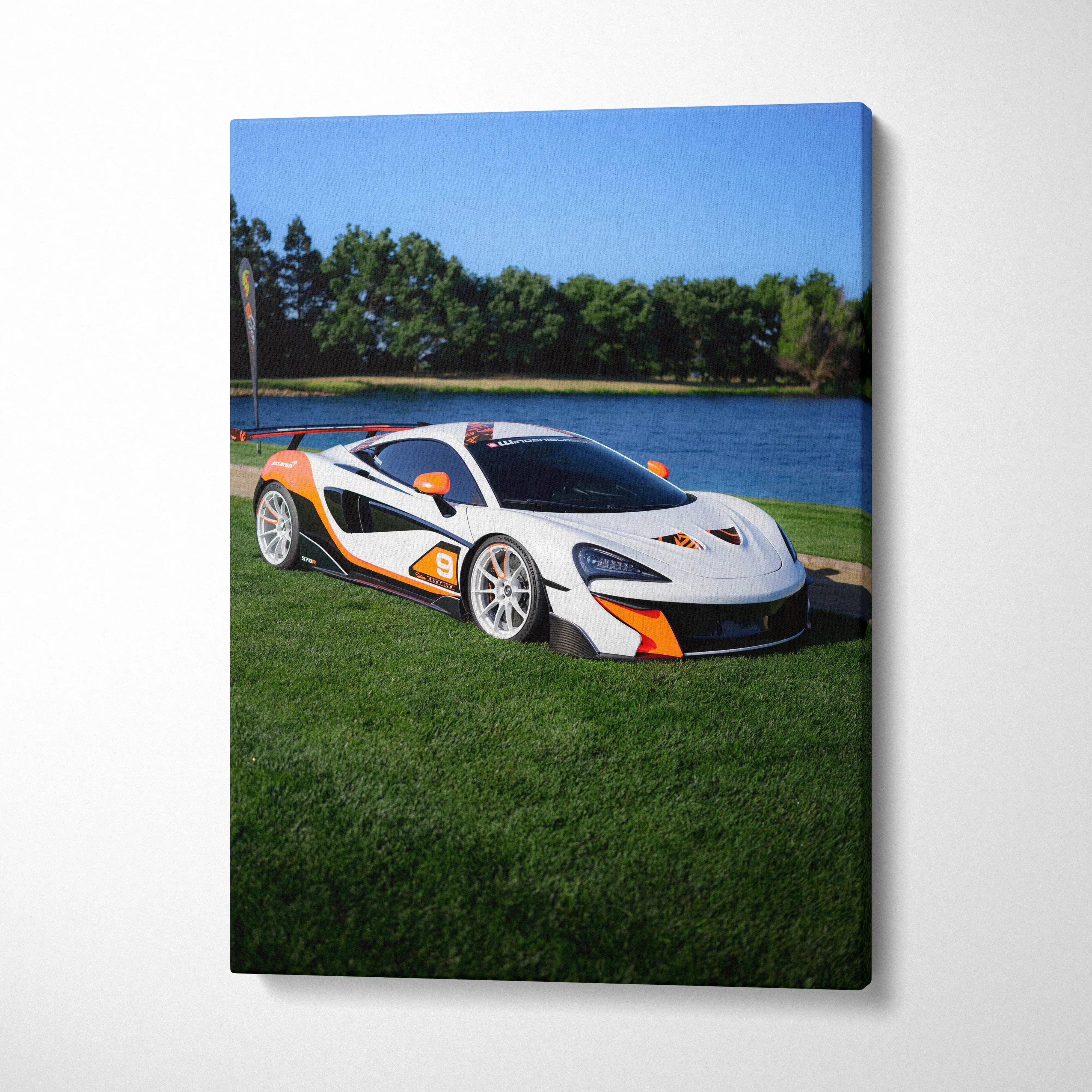 Vertical canvas art featuring a white and orange McLaren 570S on grass by a lake, vibrant wall art.
