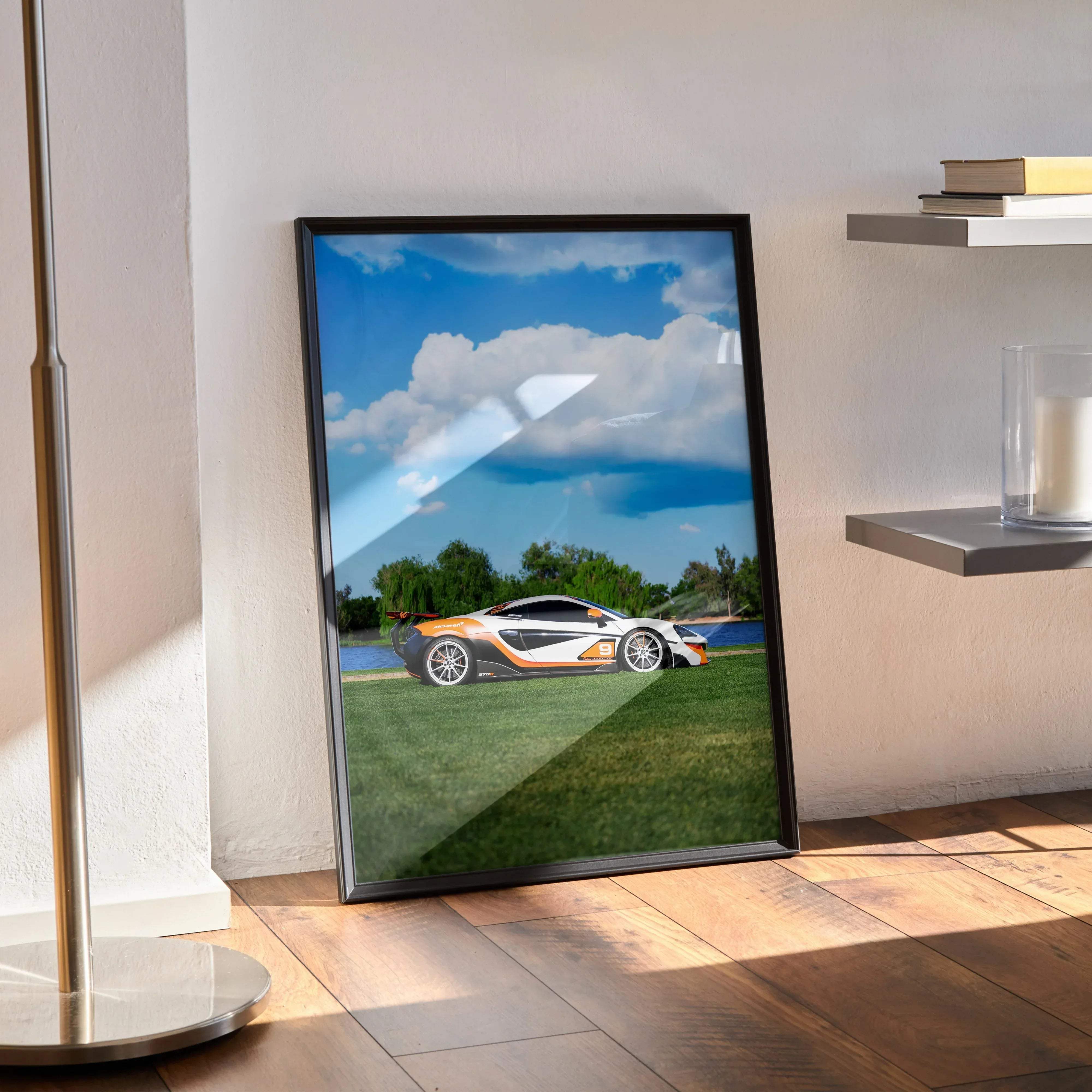 Black-framed poster featuring a white and orange mclaren 570s sports car under a blue sky with clouds
