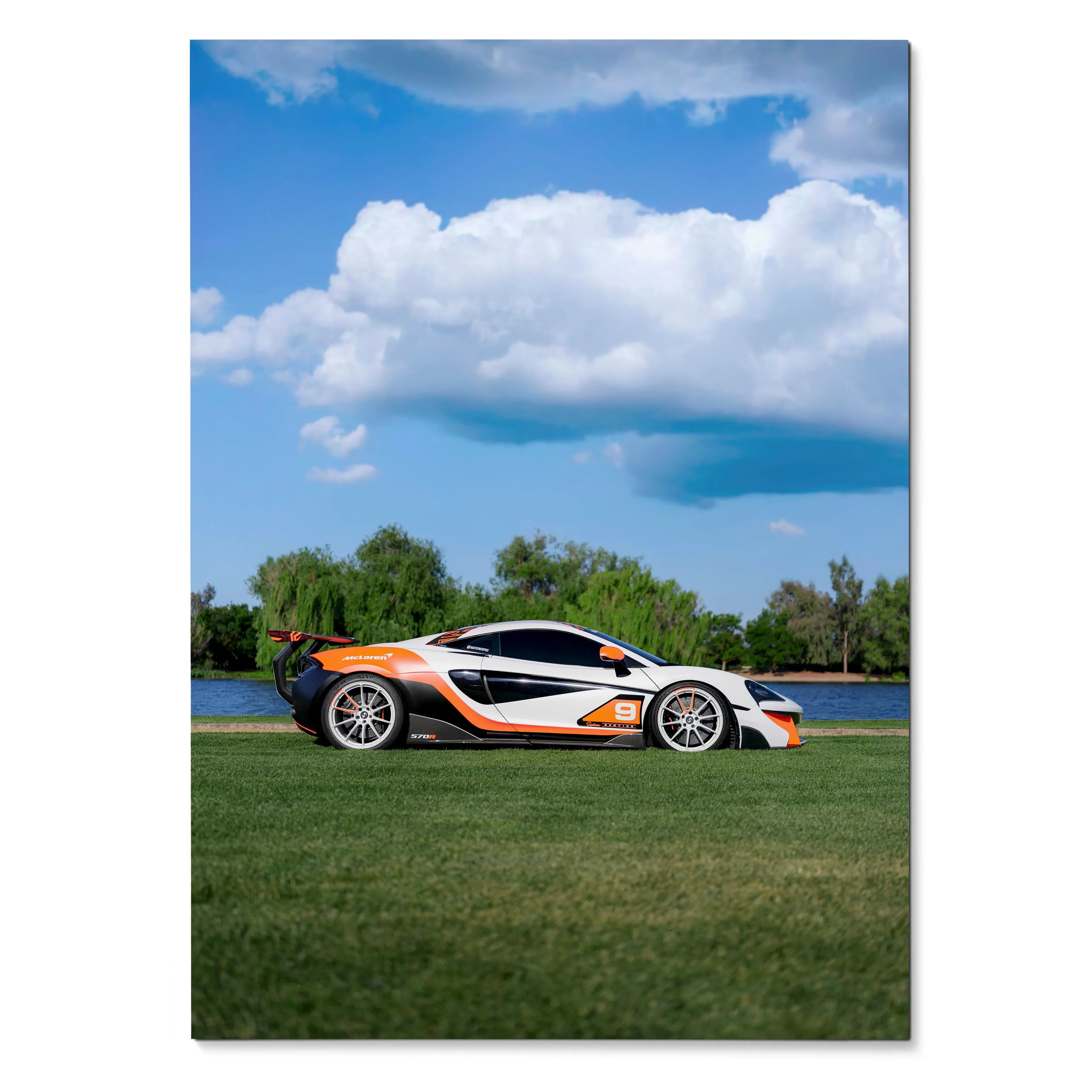 McLaren 570S racing car in white and orange on grass with blue sky poster wall art.
