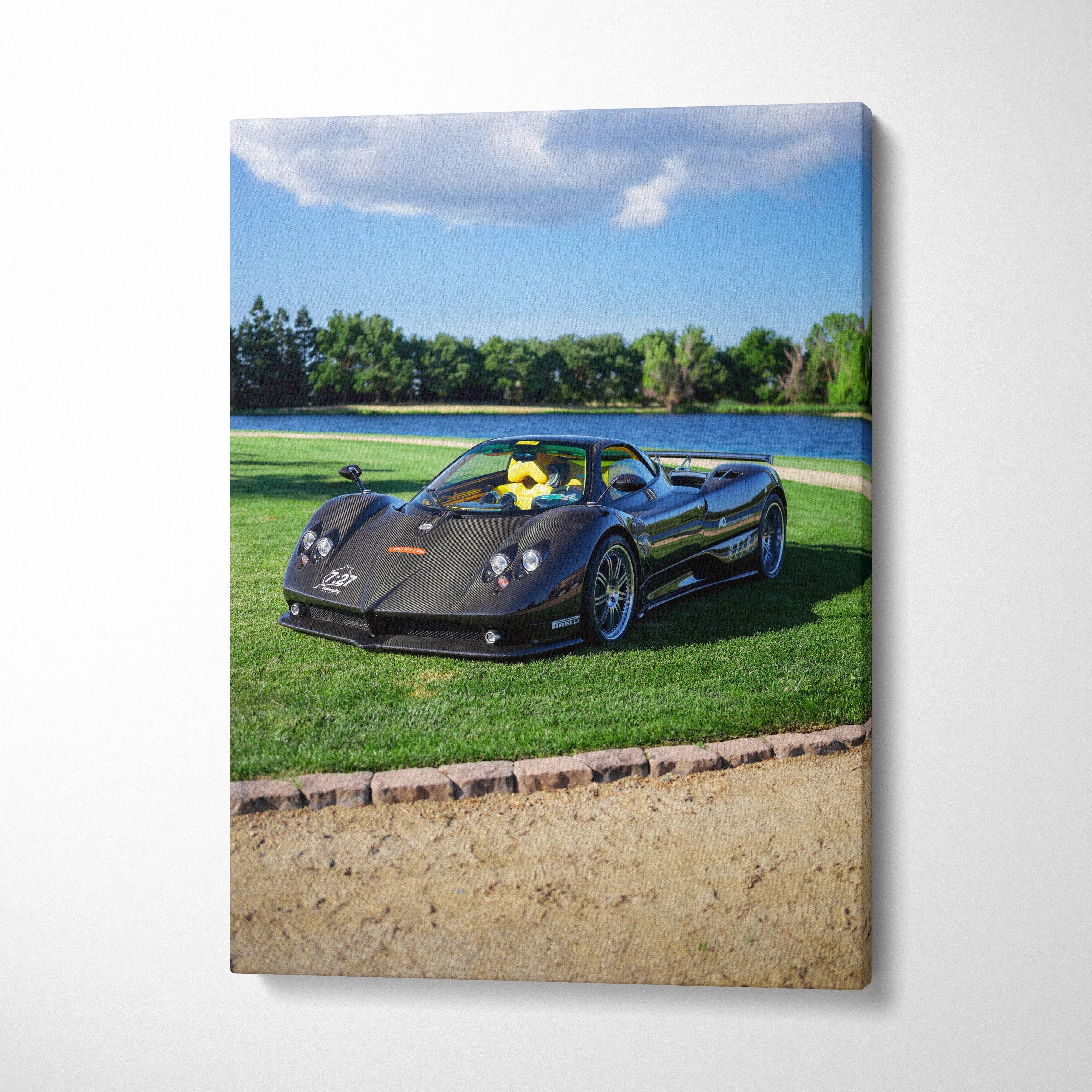 Vertical canvas wall art featuring a black Pagani Zonda F Clubsport on grass by a lake under blue sky.