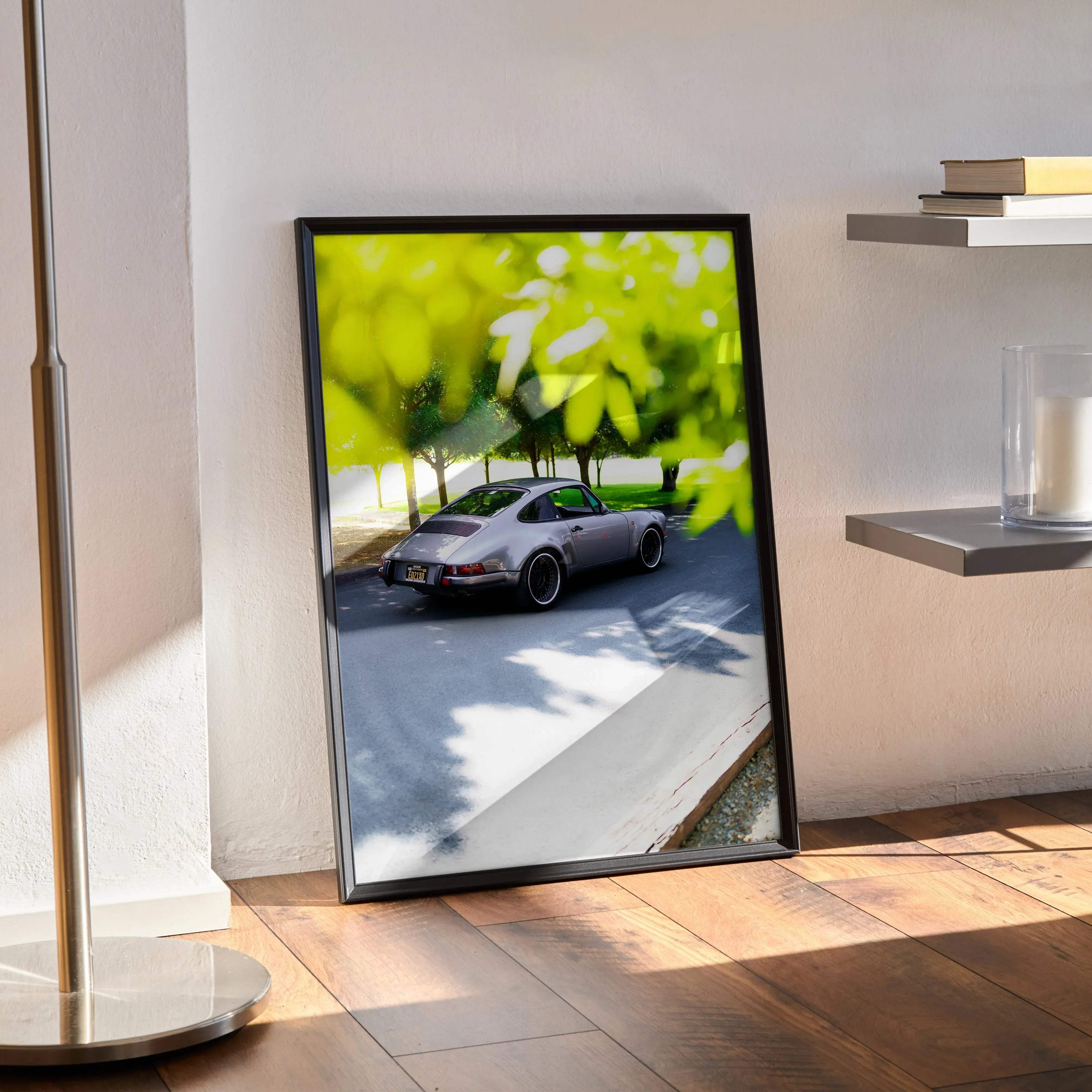 Black-framed poster of a silver porsche 911 speeding through a sunlit leafy street porsche 911 classic car poster