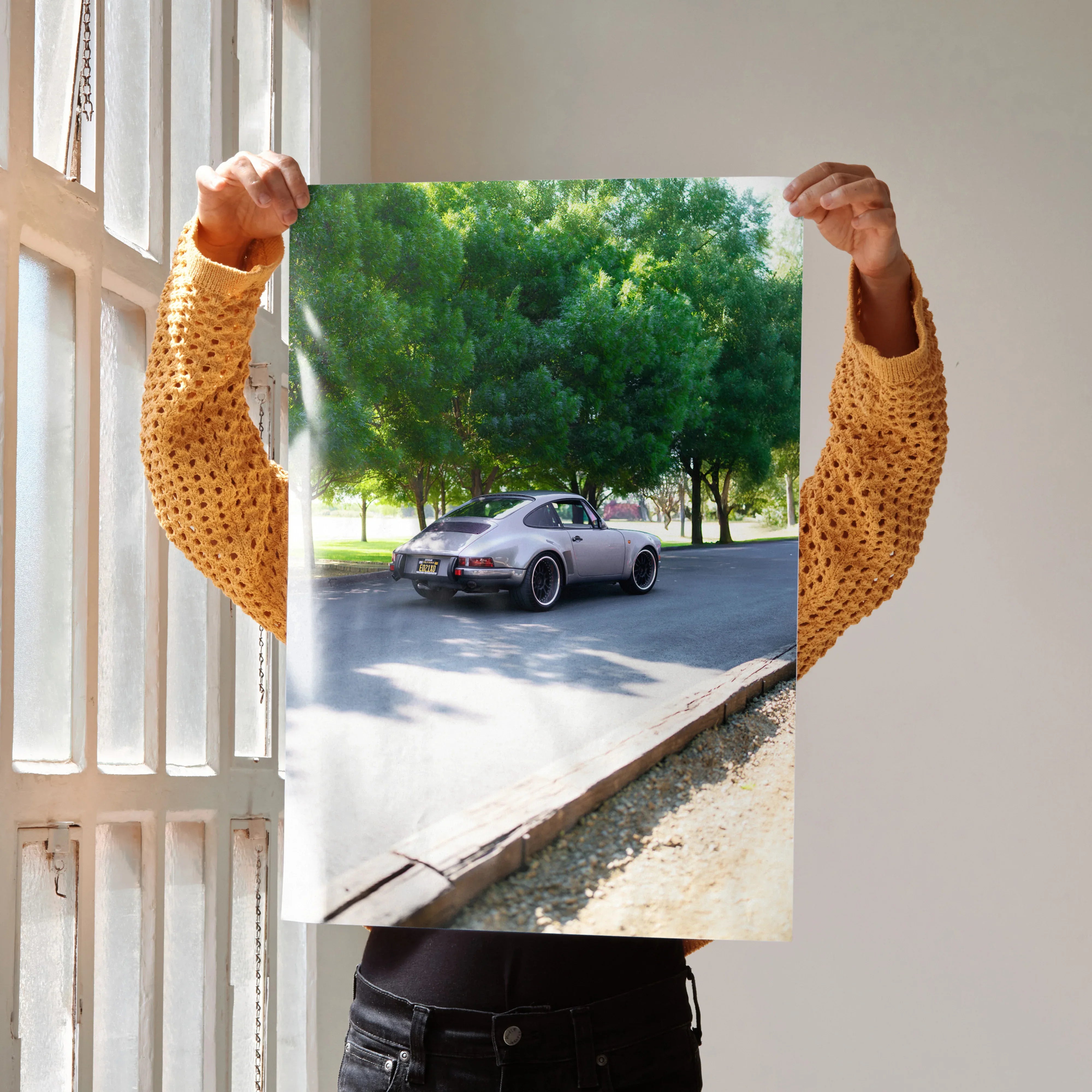 Poster of classic silver Porsche 911 driving near green trees, vibrant wall art.
