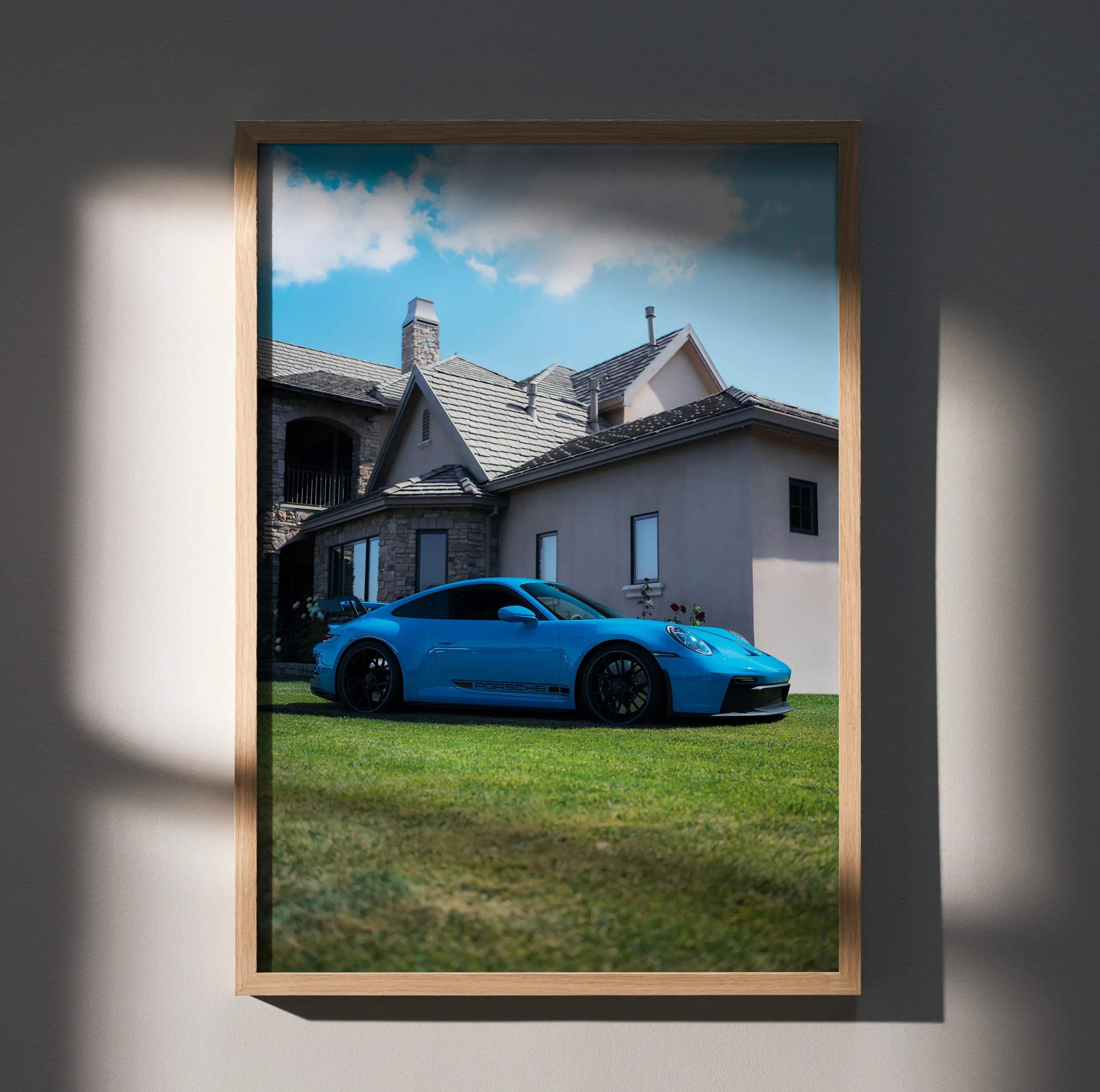 A vibrant blue porsche 911 gt3 sports car on green grass before a stone house in a high resolution framed poster