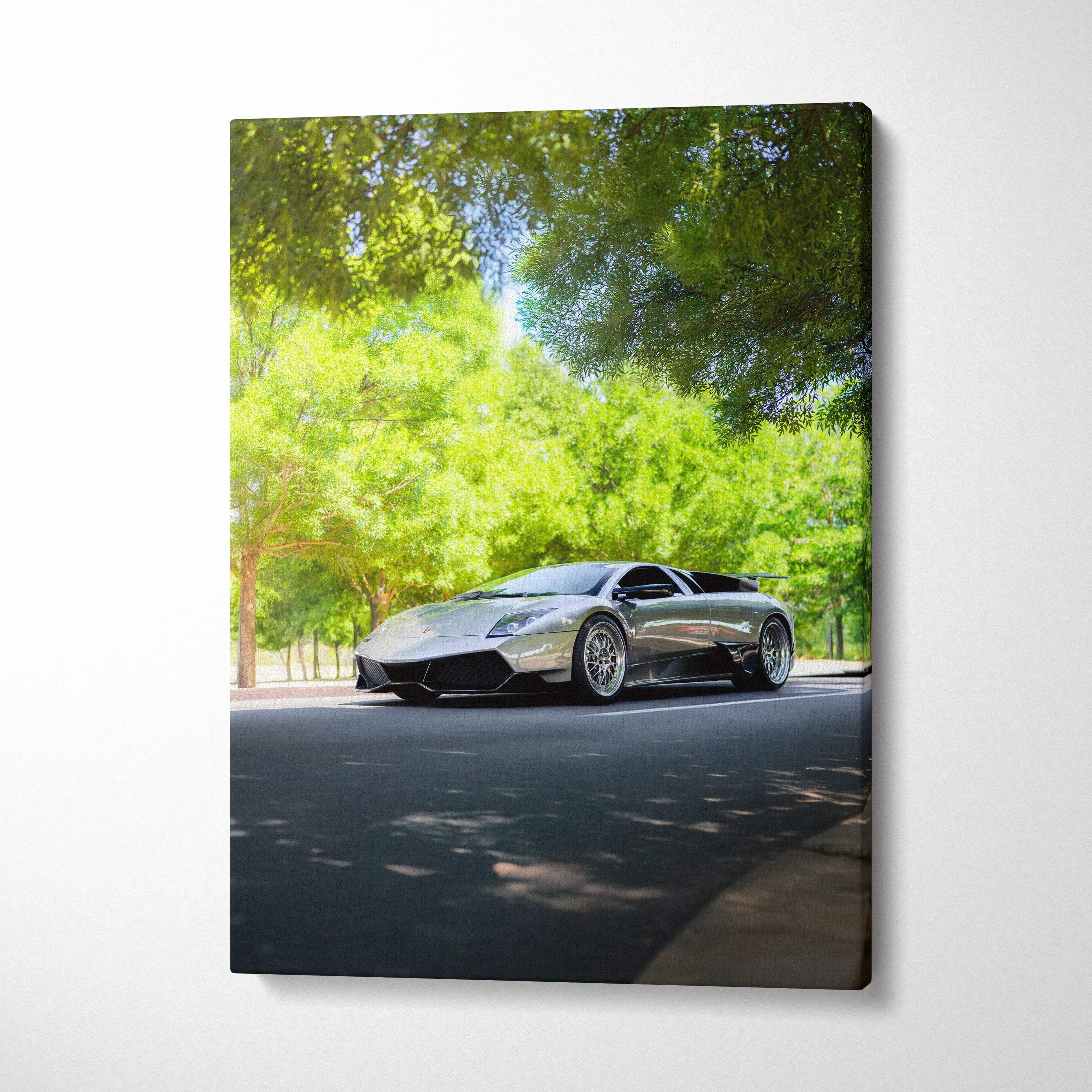 Vertical canvas art of a sleek black Lamborghini Murcielago parked on a sunlit road with green trees backdrop.
