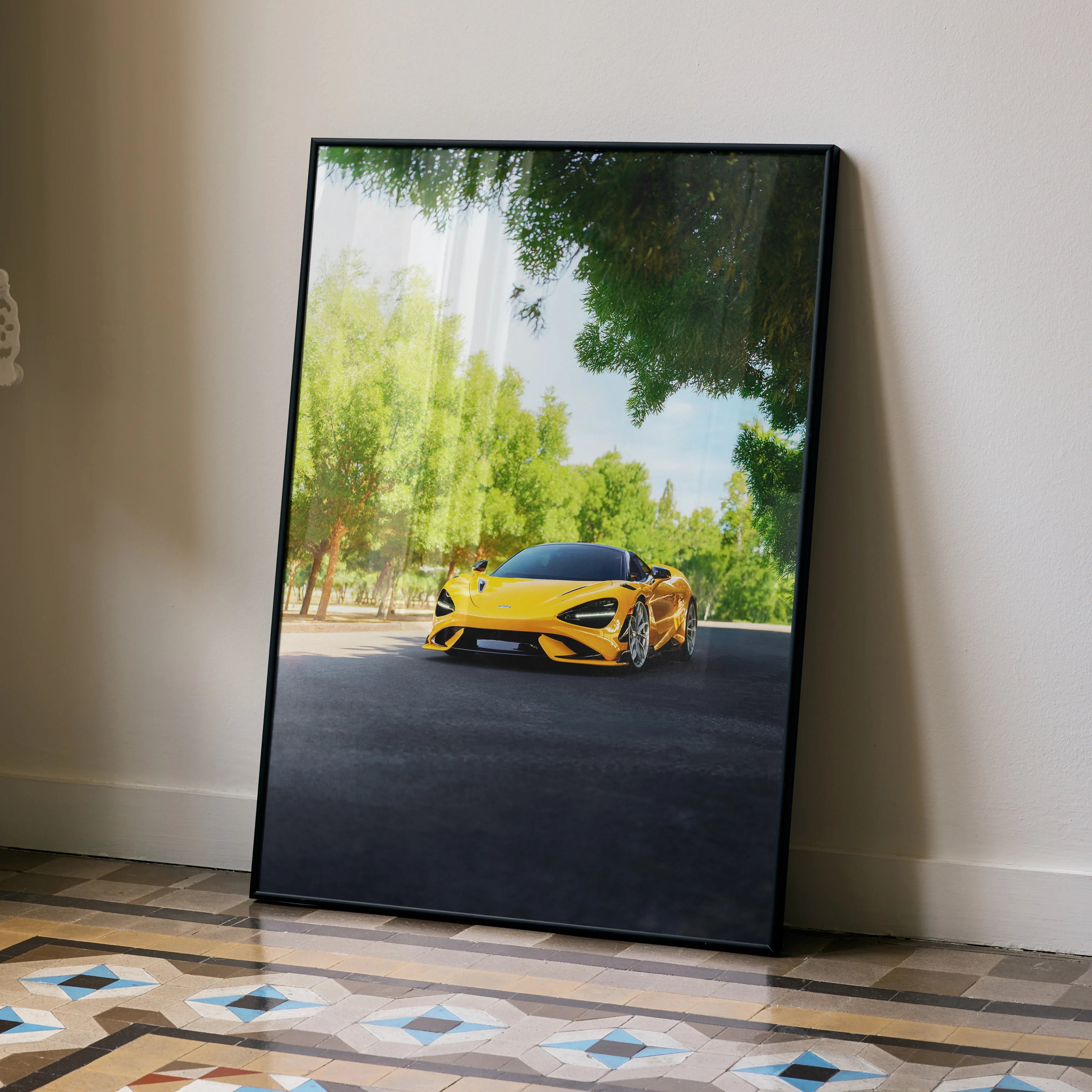 McLaren 765LT poster with vibrant yellow sports car on road, framed wall art leaning against neutral wall.