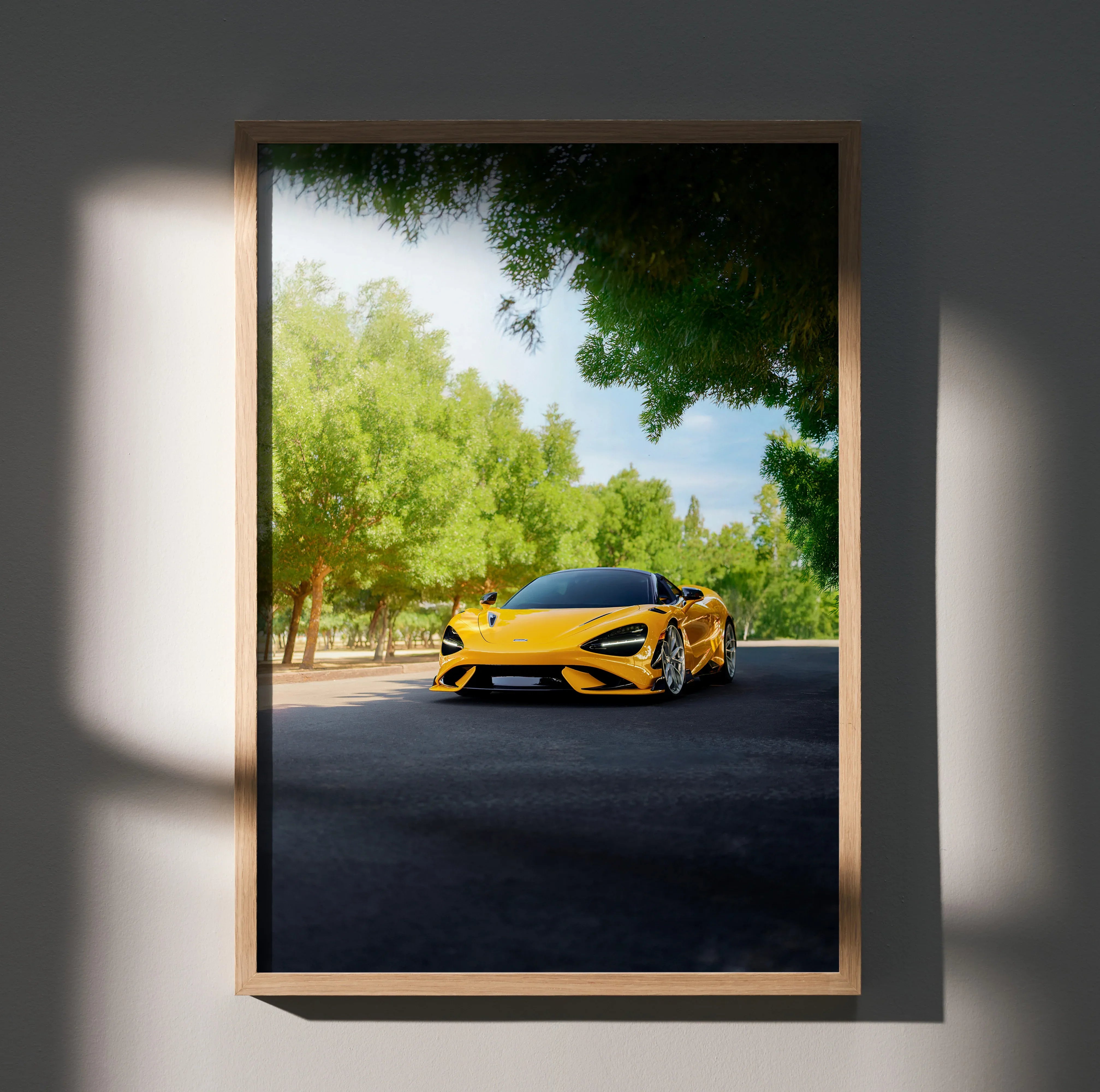 Yellow McLaren 765LT driving on tree-lined road wall art poster in wooden frame.
