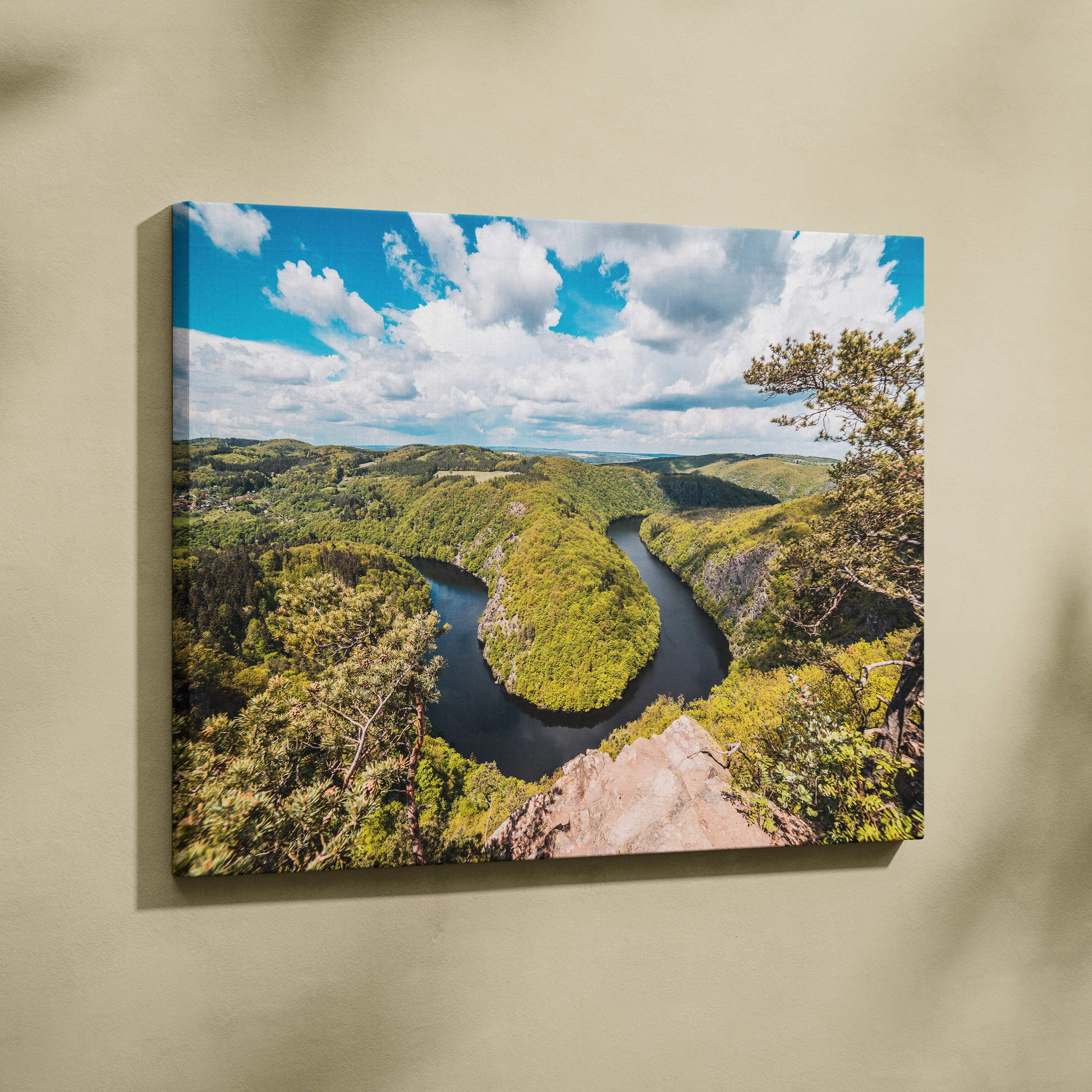 Canvas print of meandering river through lush green forest valleys under blue sky