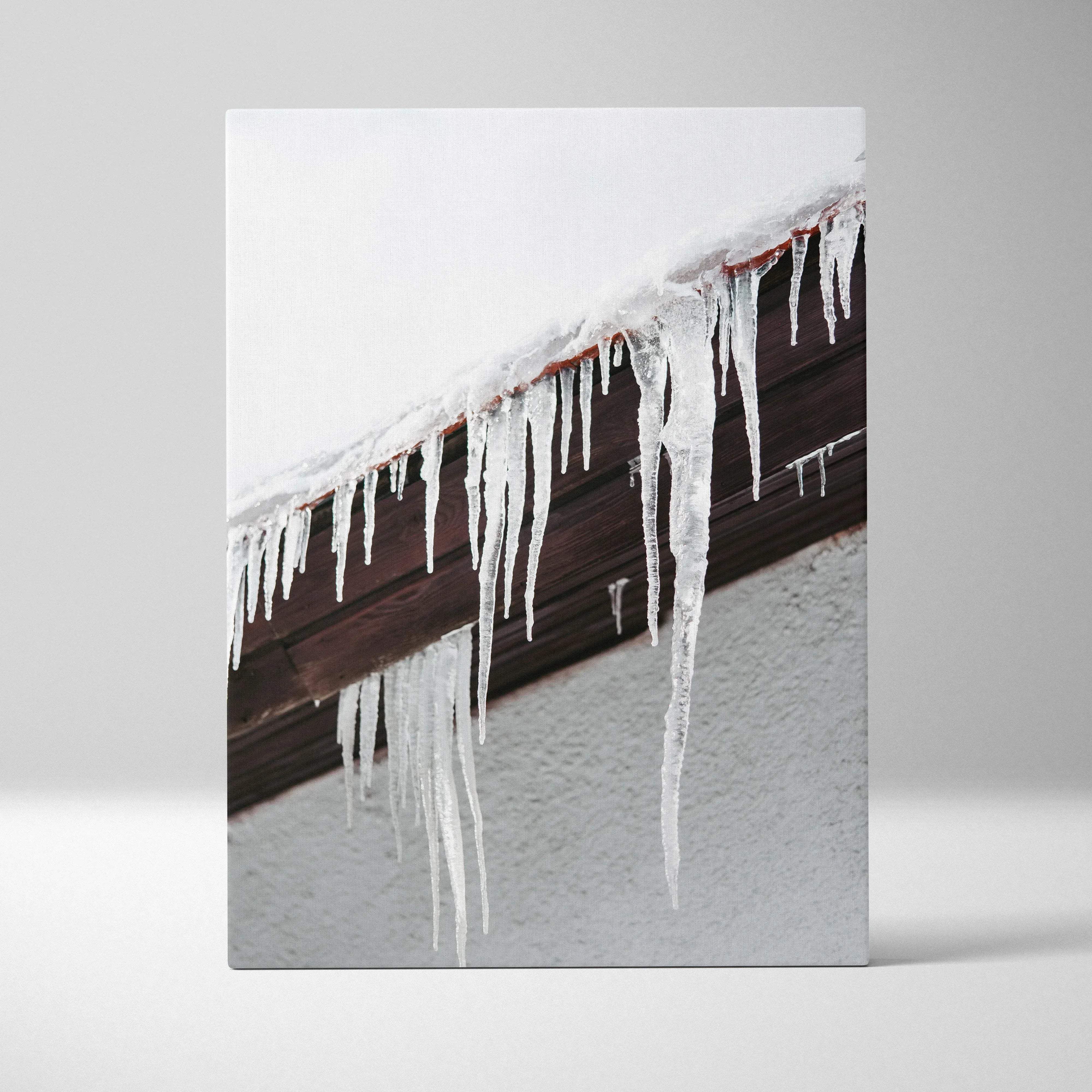 A canvas print of translucent white icicles hanging from a snow-covered roof edge against dark wood rustic decor