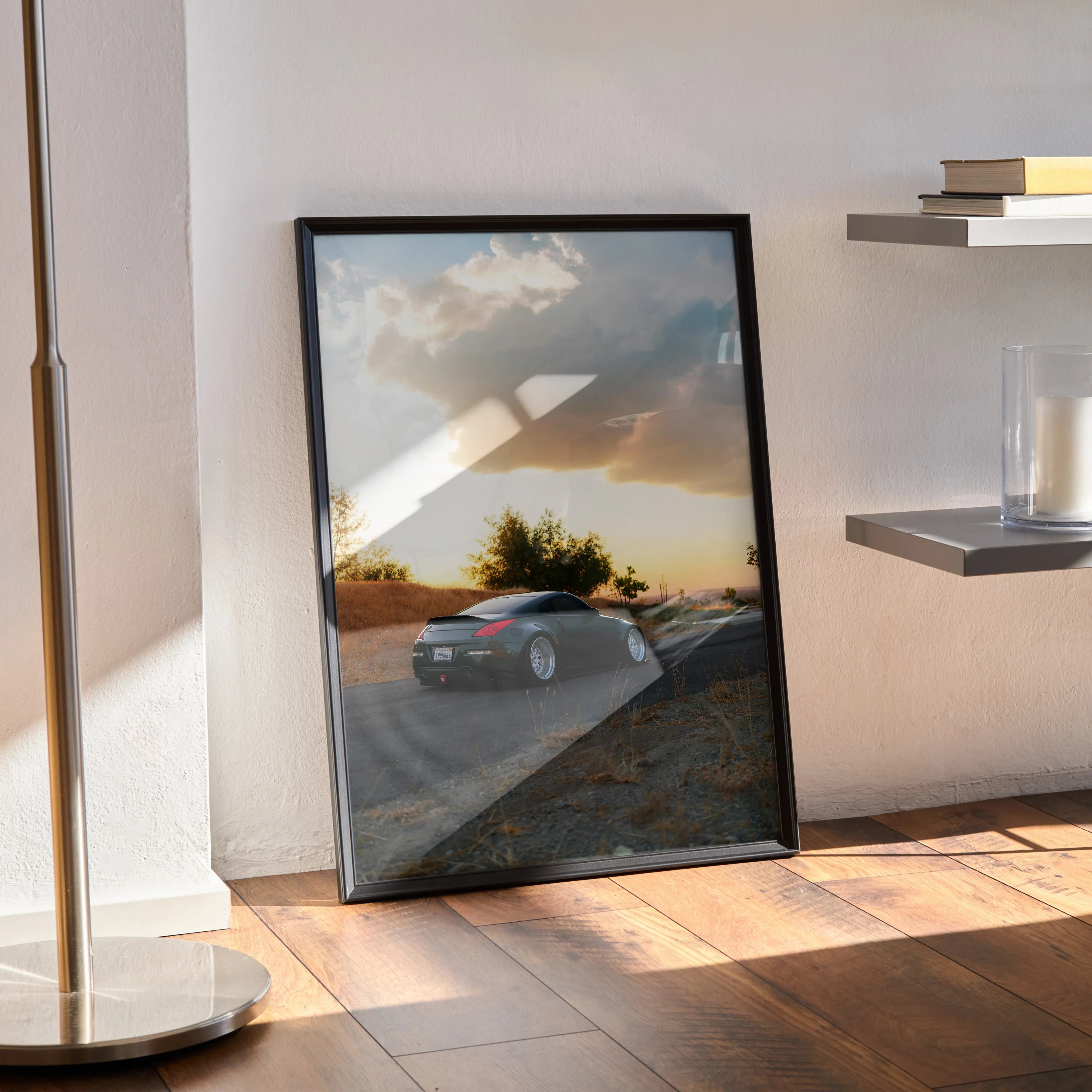 Nissan 350z car poster with sunset background framed as wall art leaning against wall on wooden floor.