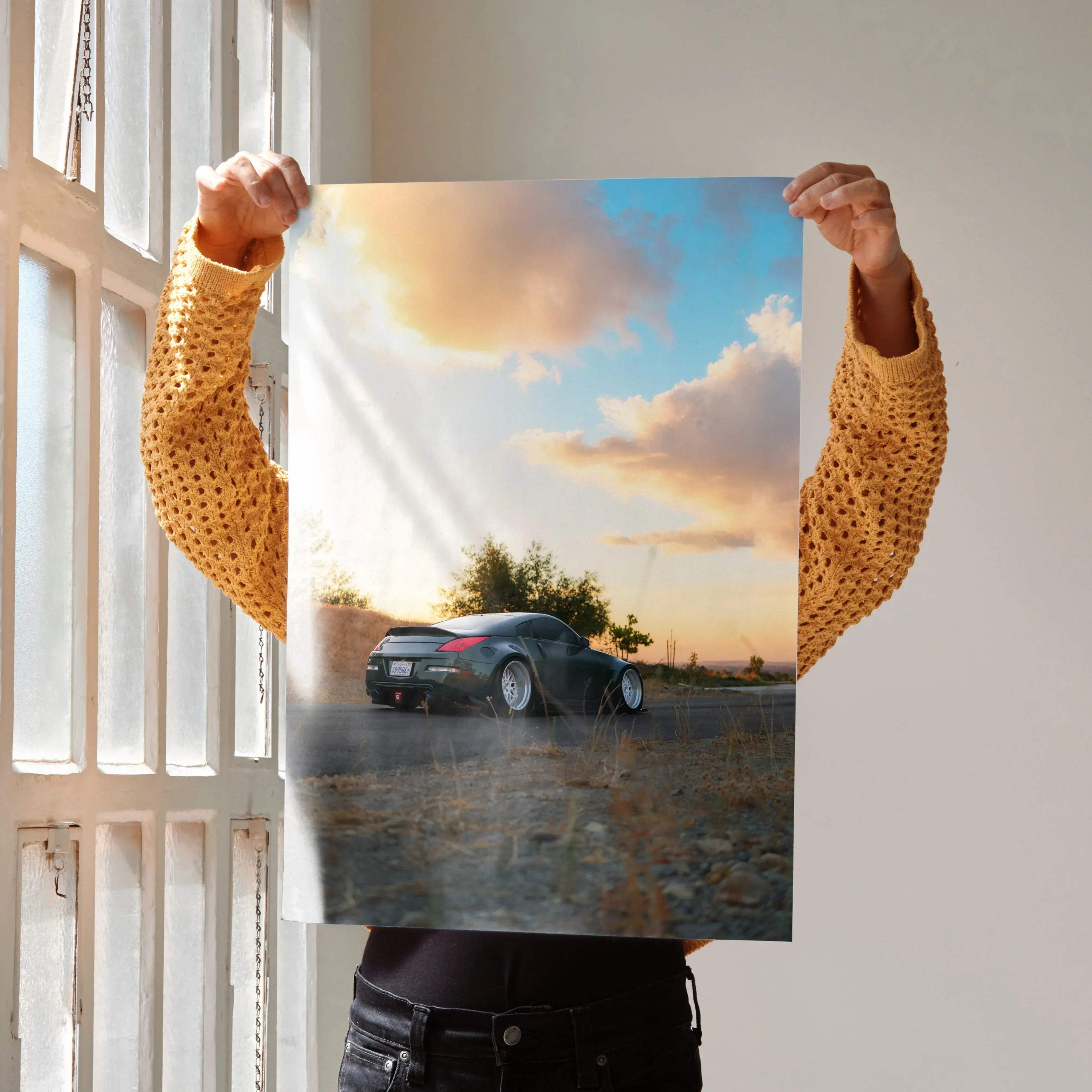 A dark green nissan 350z sports car poster showing a dynamic rear view against a sunset sky with soft clouds