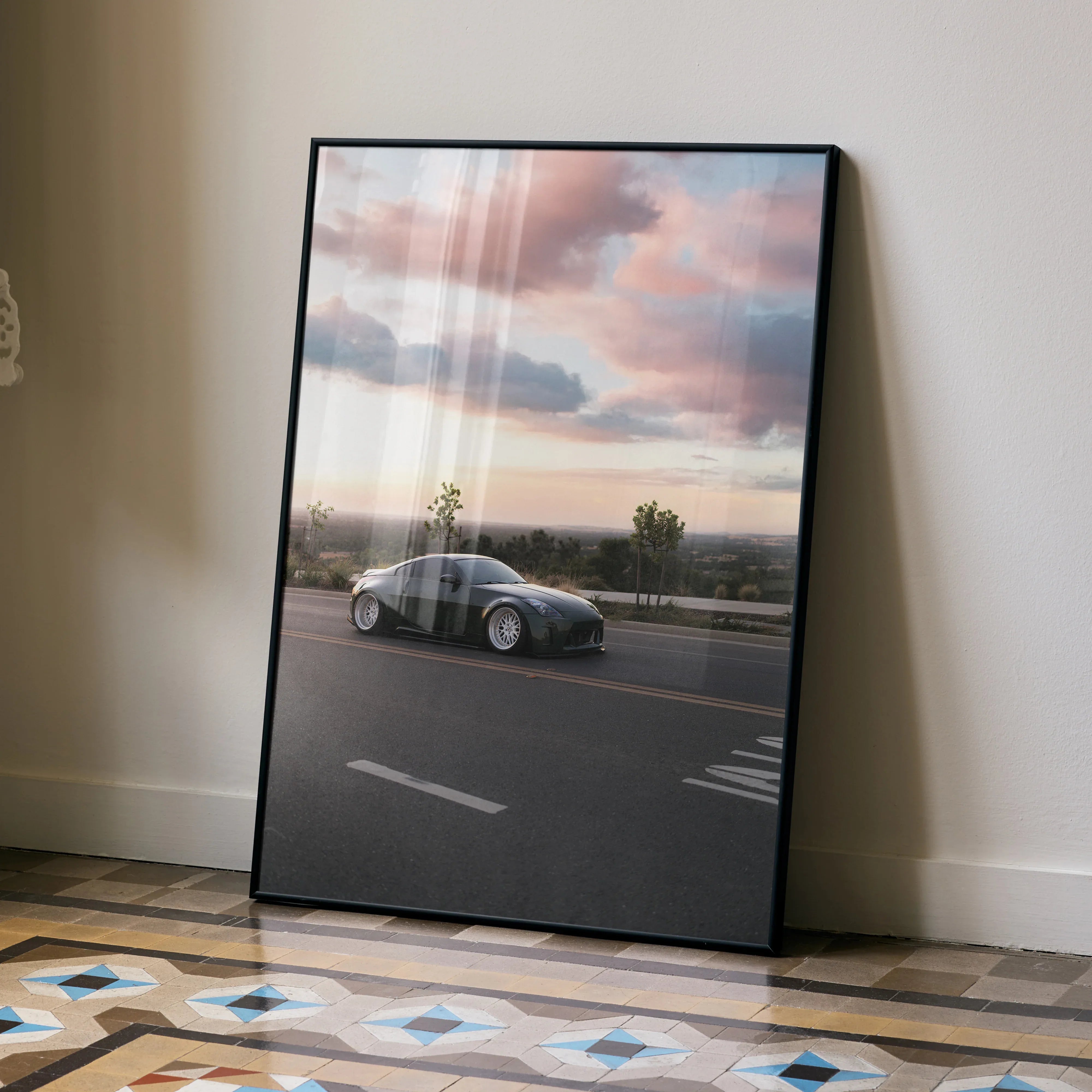 Nissan 350z driving at sunset wall art poster with pink and purple clouds in black frame.