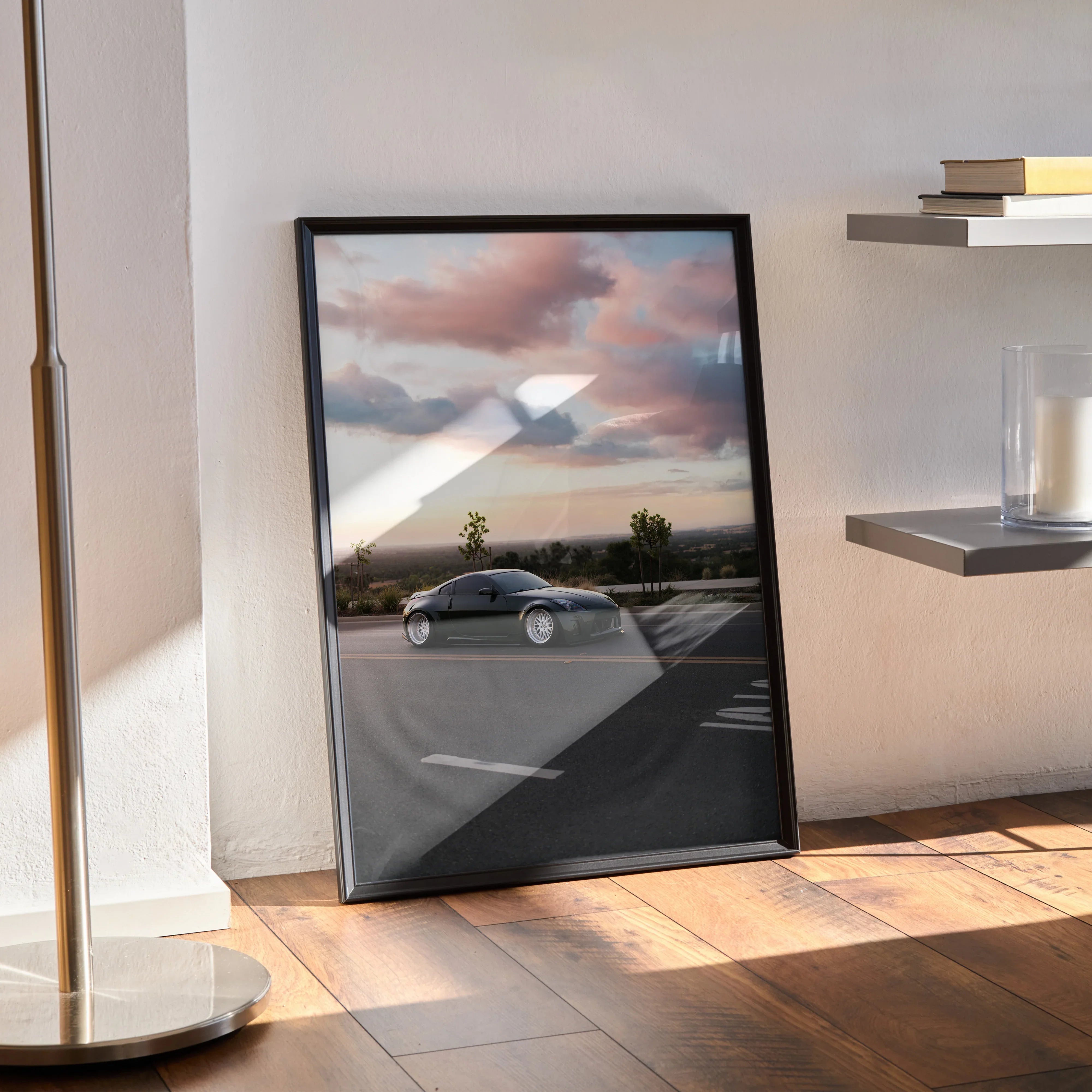 Nissan 350z poster wall art featuring sleek silver car under dramatic cloudy sky, framed and leaning on floor.