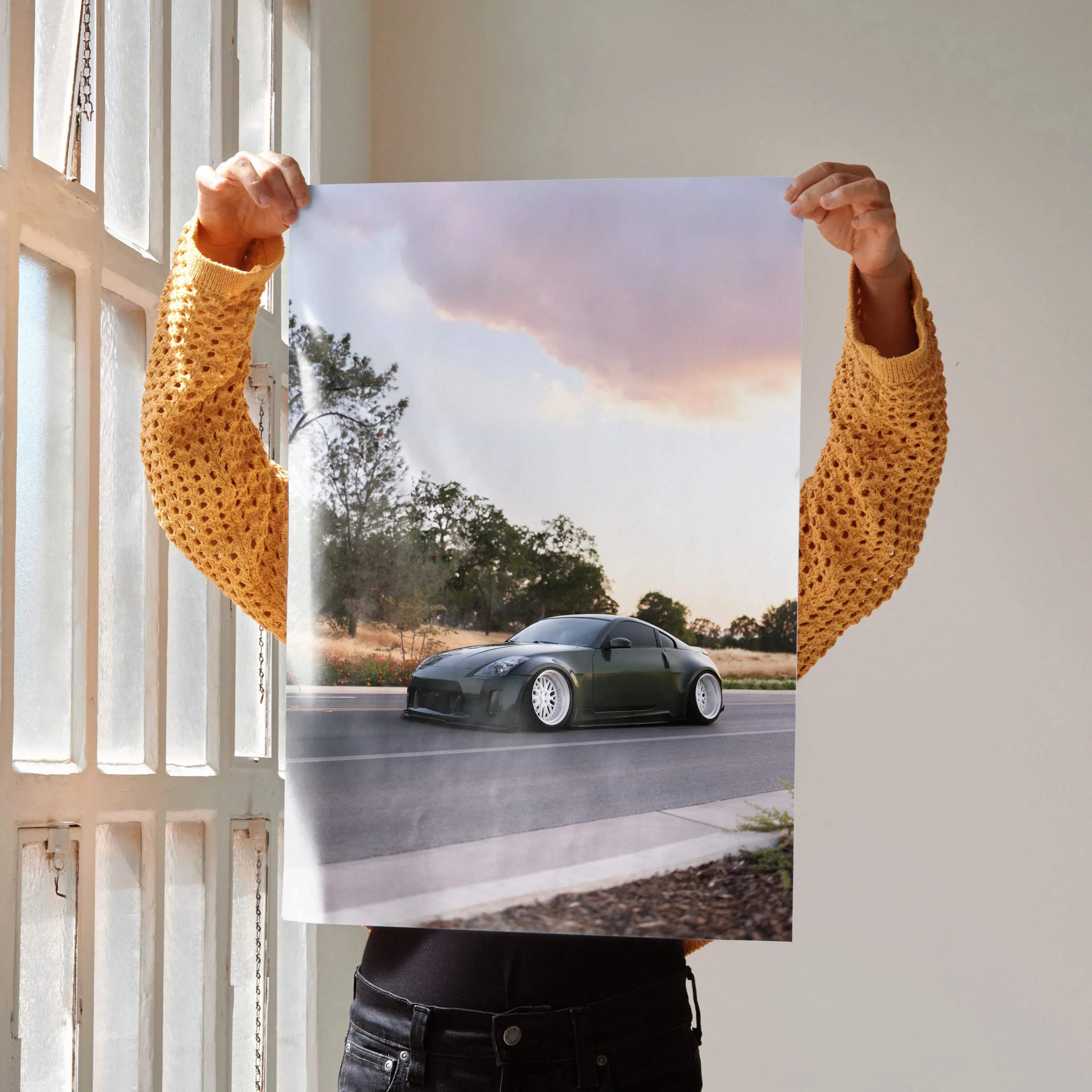 Dark green matte-finished nissan 350z sports car with white alloy wheels in motion on a paved road poster