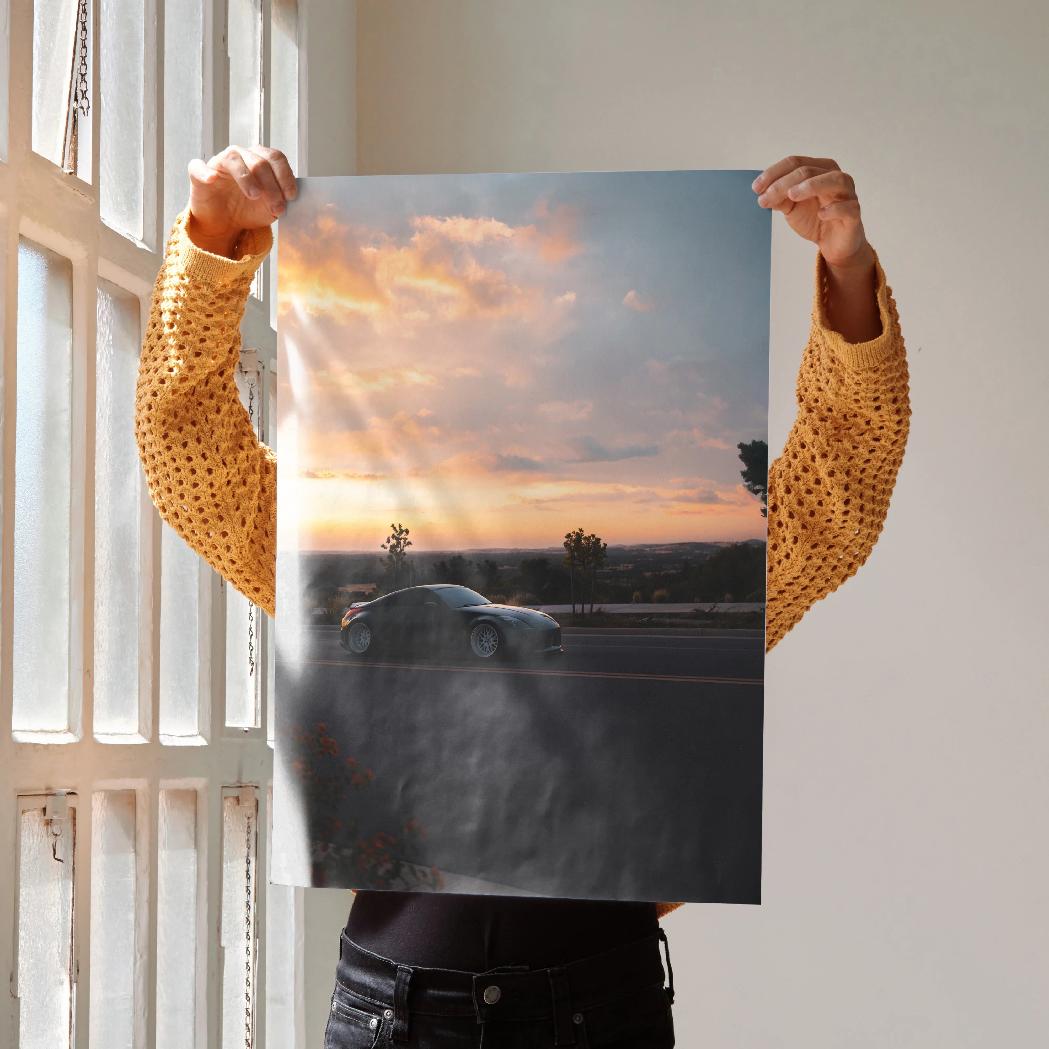 Nissan 350z driving at sunset poster wall art with vibrant sky and road scene.