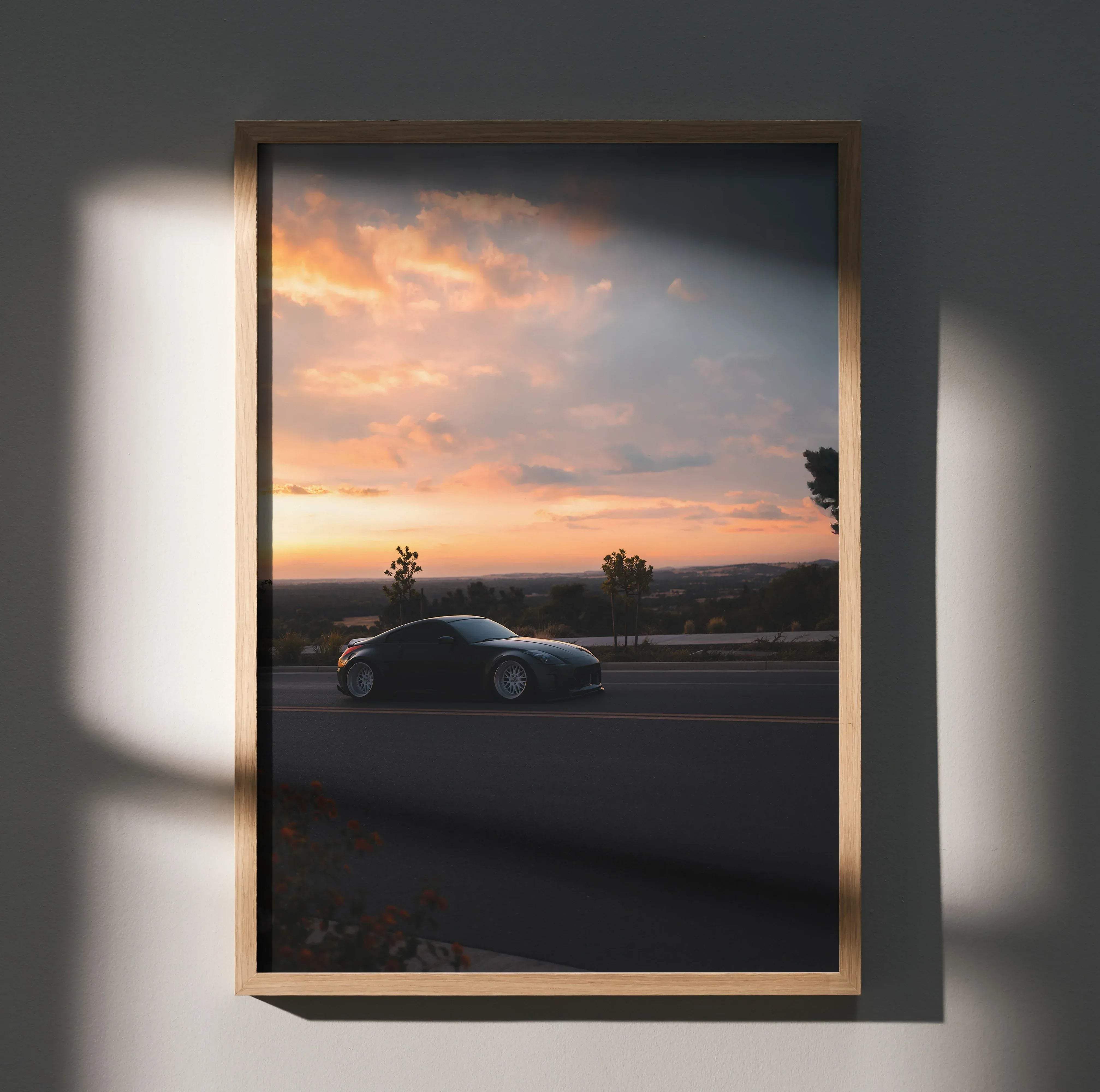A sleek black nissan 350z sports car poster in high resolution framed in light wood showing motion at sunset