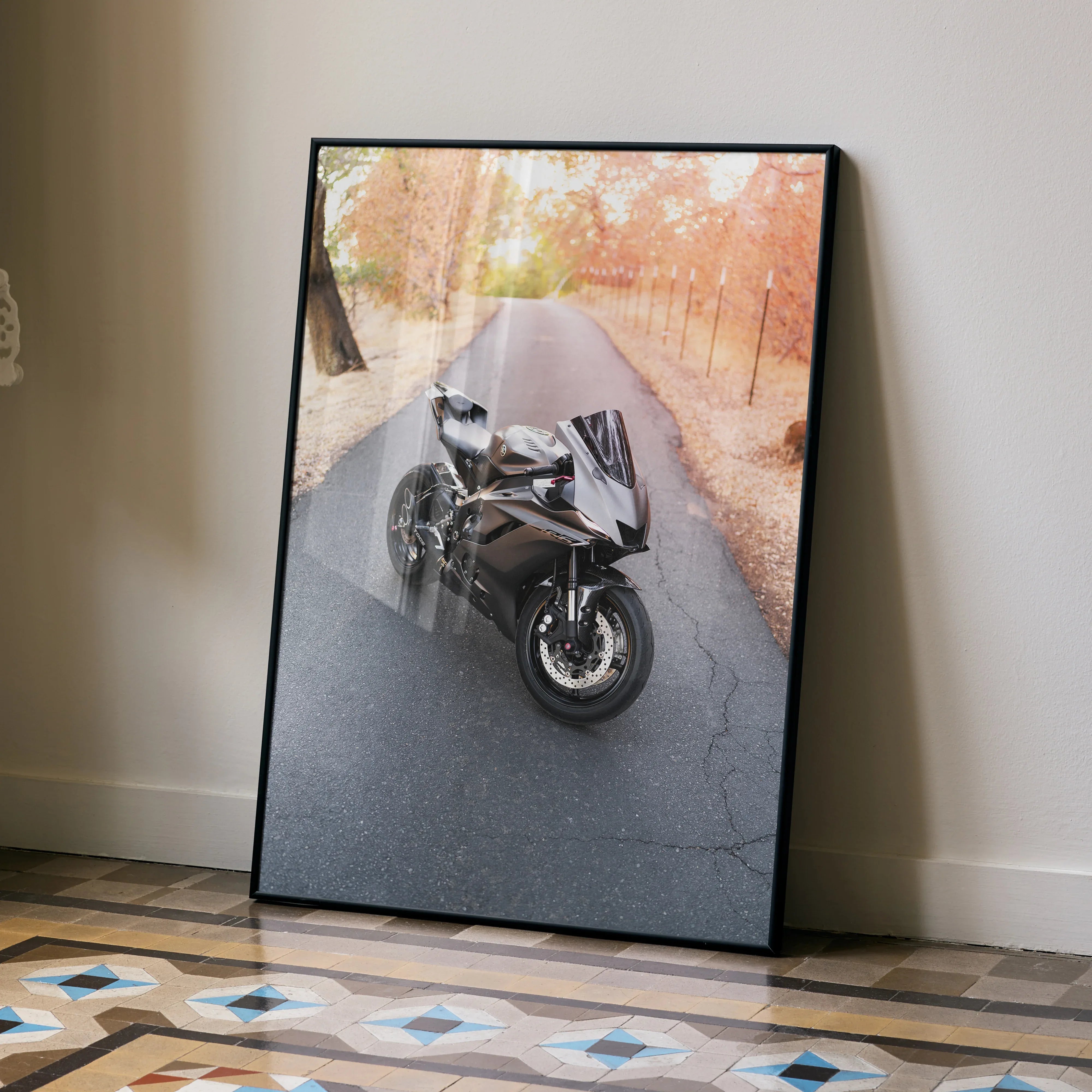 Black-framed Yamaha R6 motorcycle poster leaning against white wall on patterned floor, wall art.