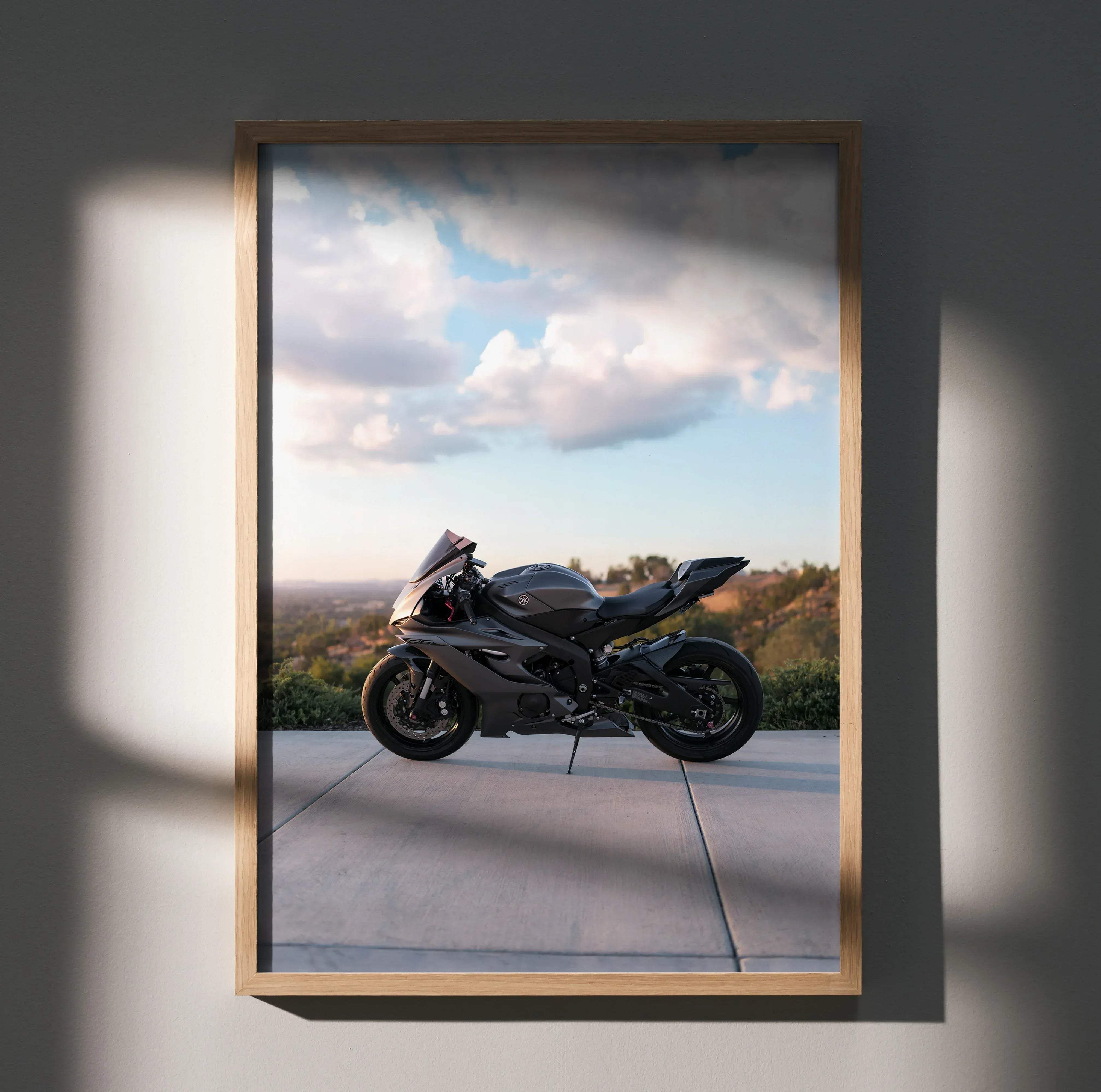 A sleek matte black yamaha r6 sport motorcycle shown in dynamic side profile inside a light wood picture frame