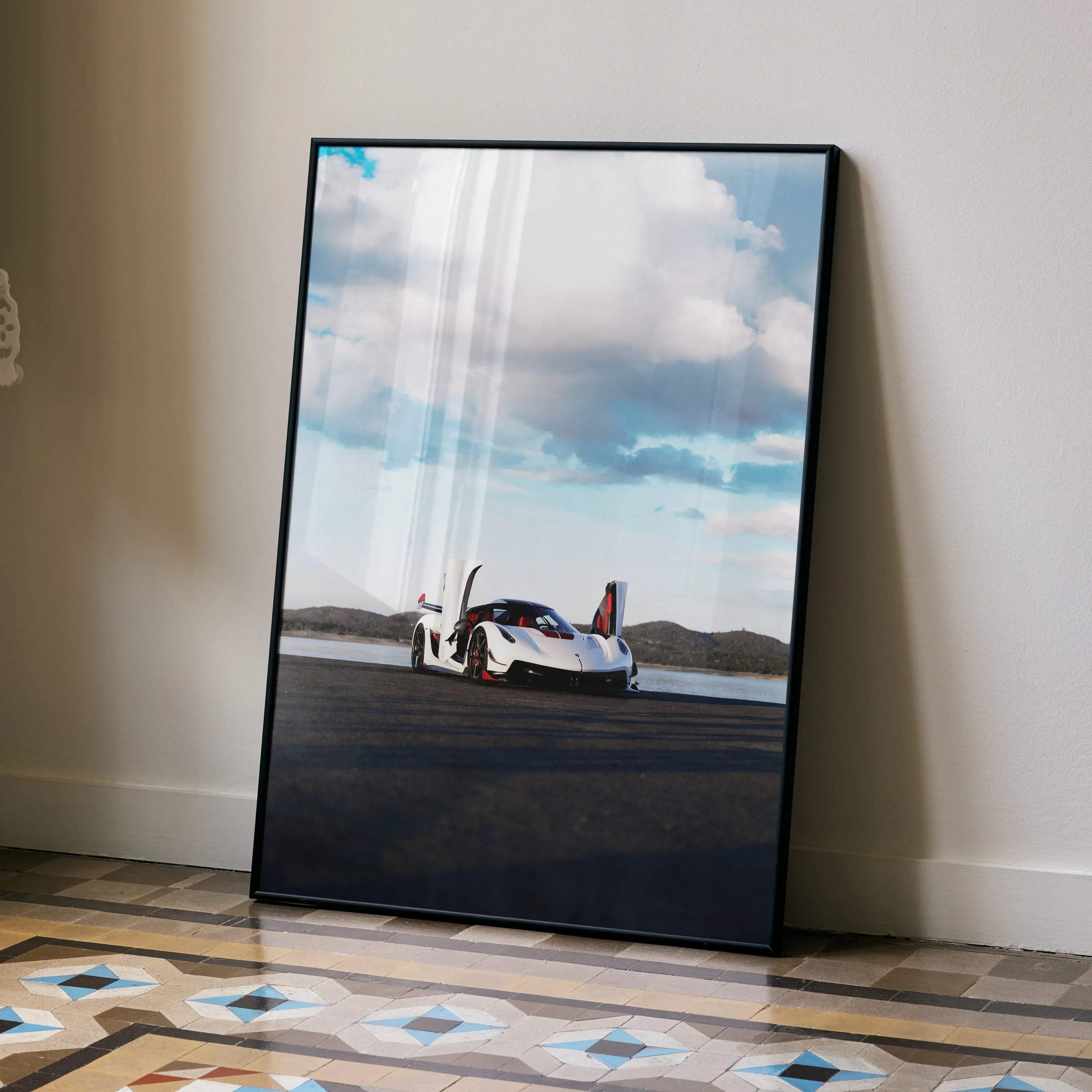 Black-framed poster of a white koenigsegg jesko sports car with red accents and open doors under a cloudy sky