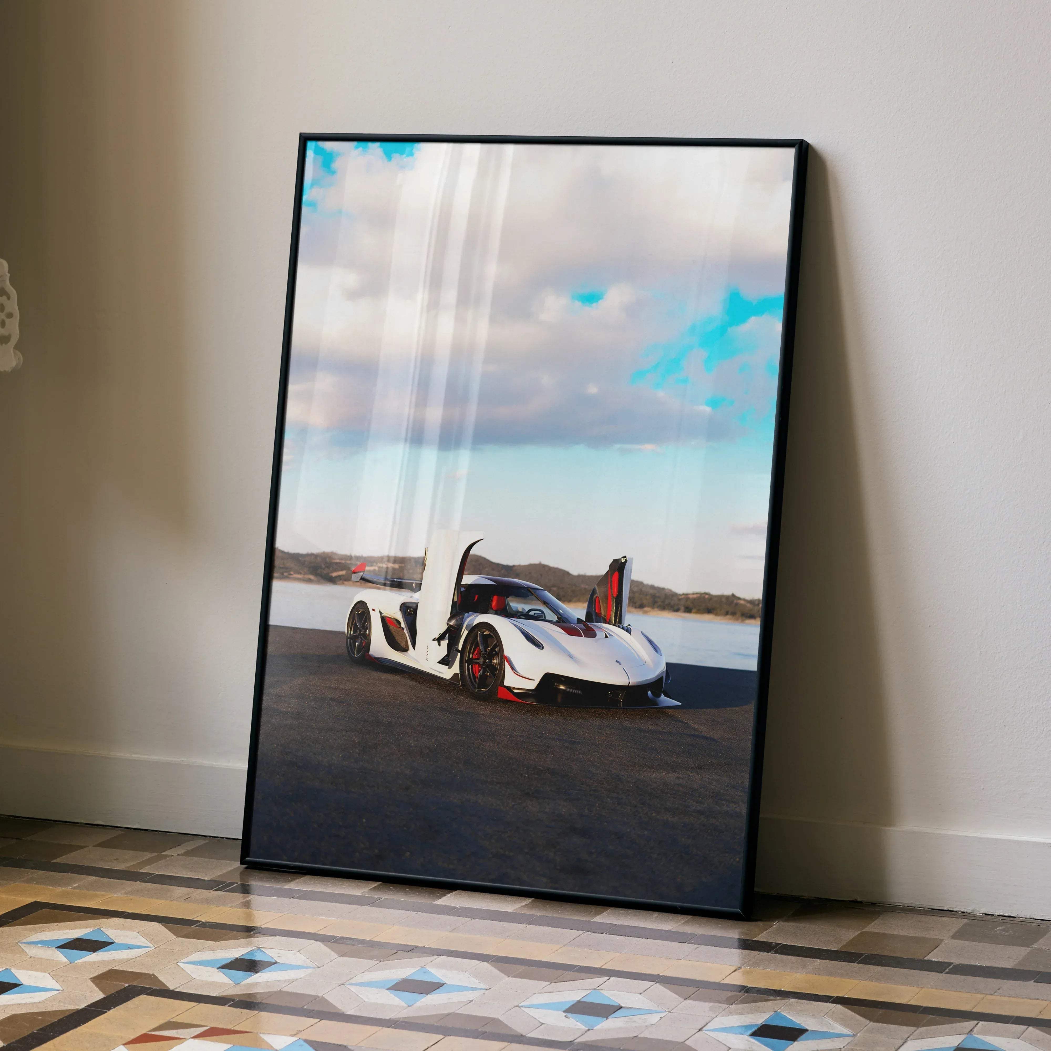 Black-framed poster of a white koenigsegg jesko hypercar with red accents and open doors against a cloudy sky