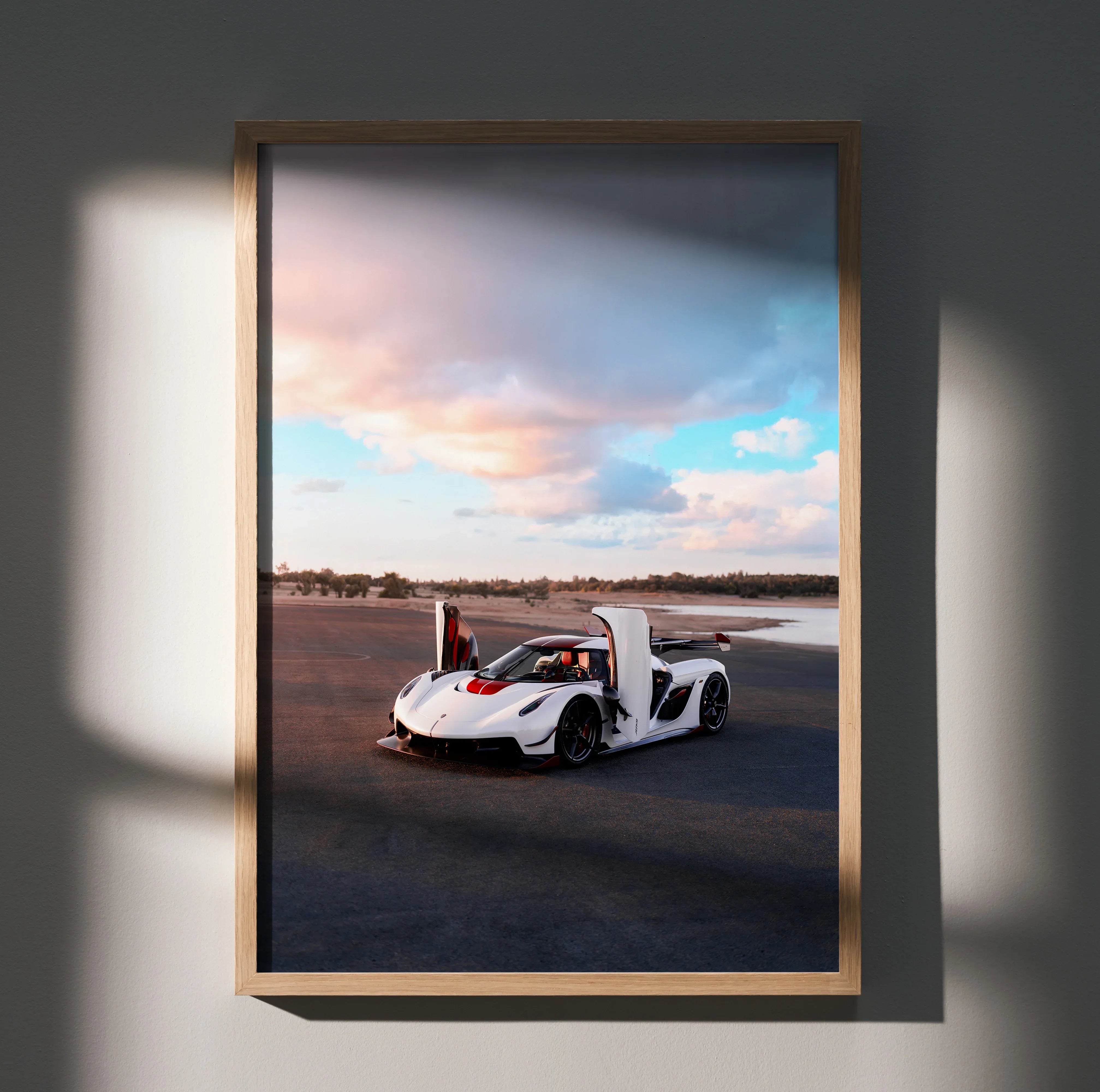 Koenigsegg Jesko sports car driving on road under dramatic sky wall art poster in wooden frame.