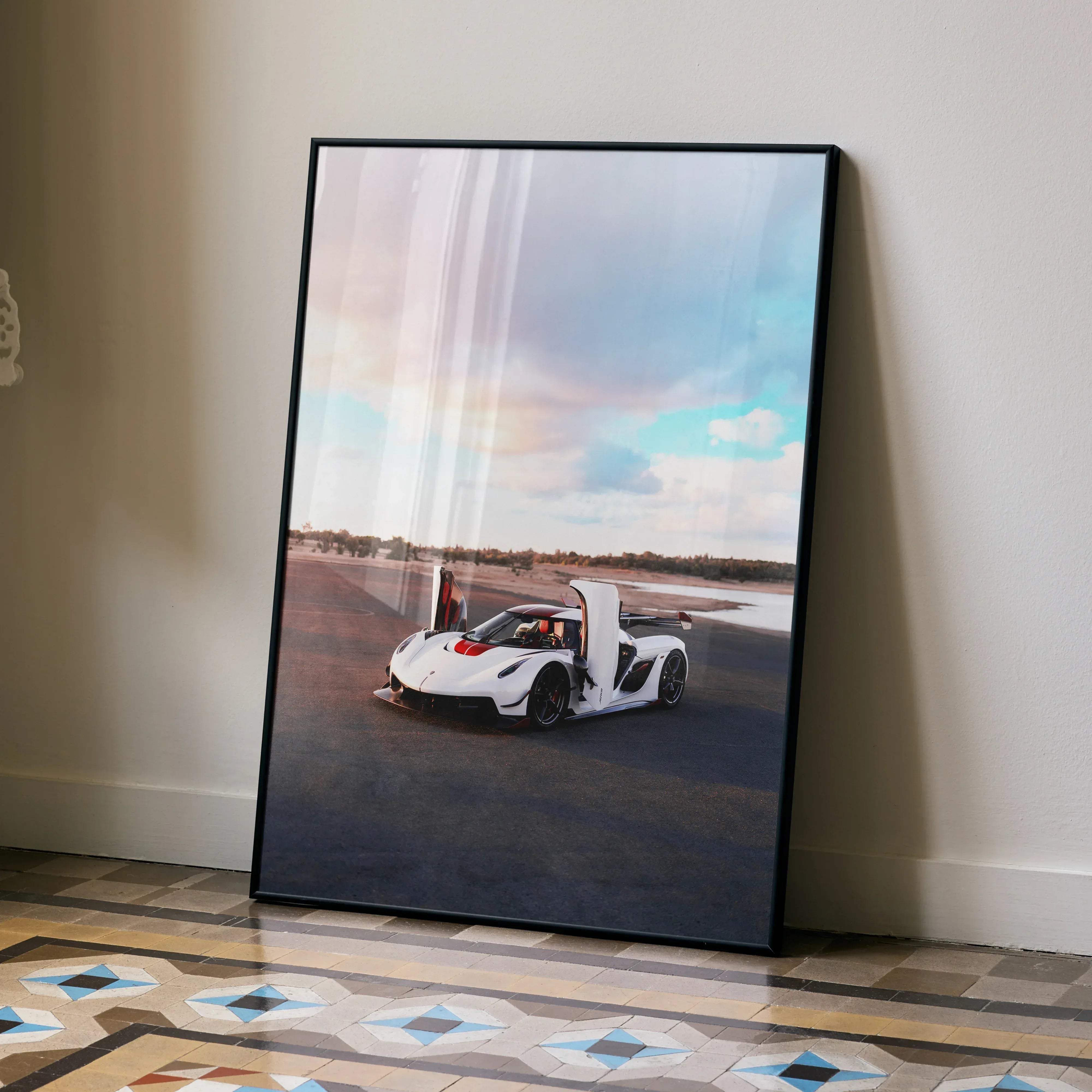 A framed Koenigsegg Jesko poster showing a white hypercar with red accents and open doors against a sky backdrop