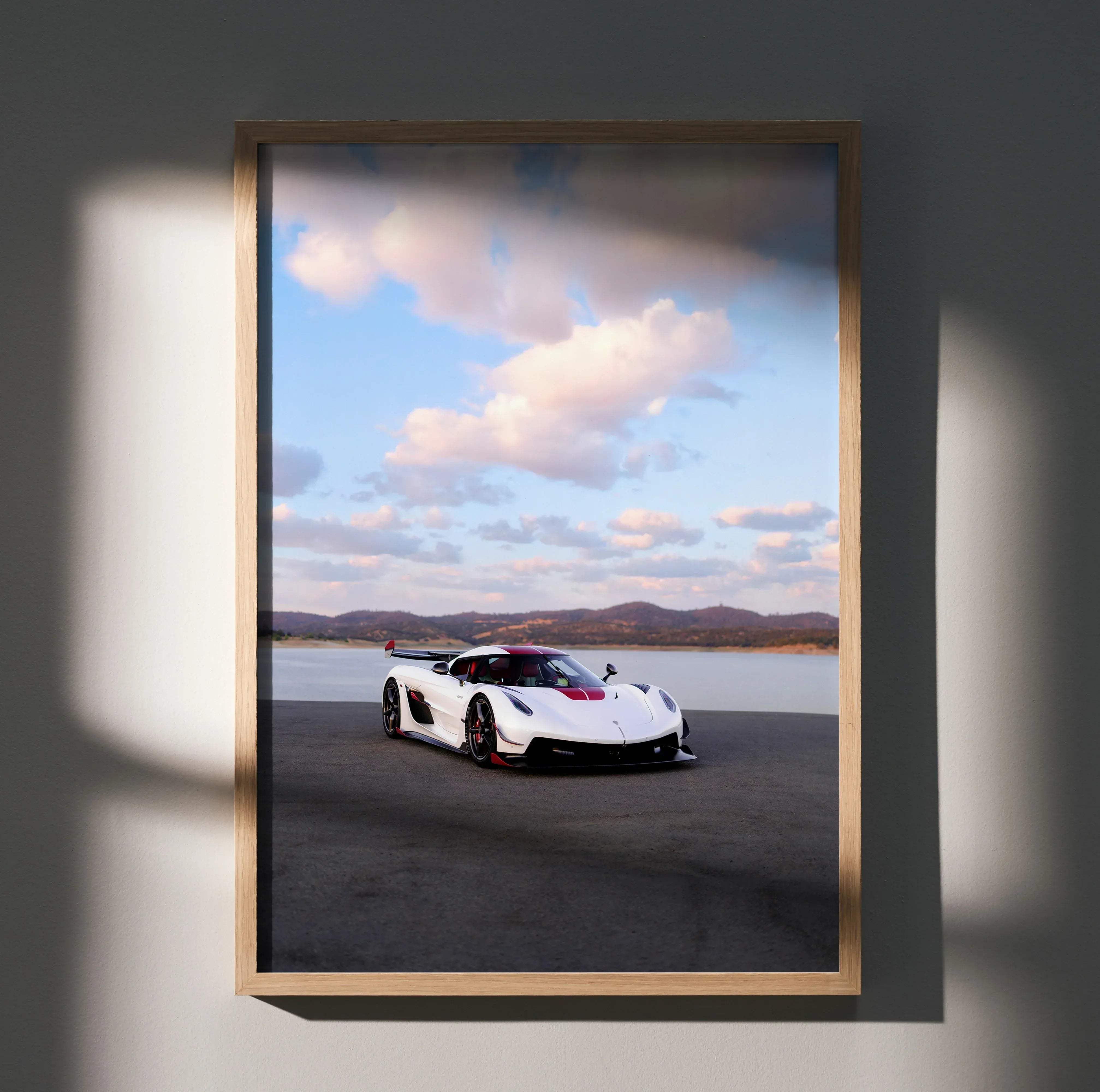 A framed high resolution koenigsegg jesko car poster featuring a white and red sports car with black accents in a light wood frame