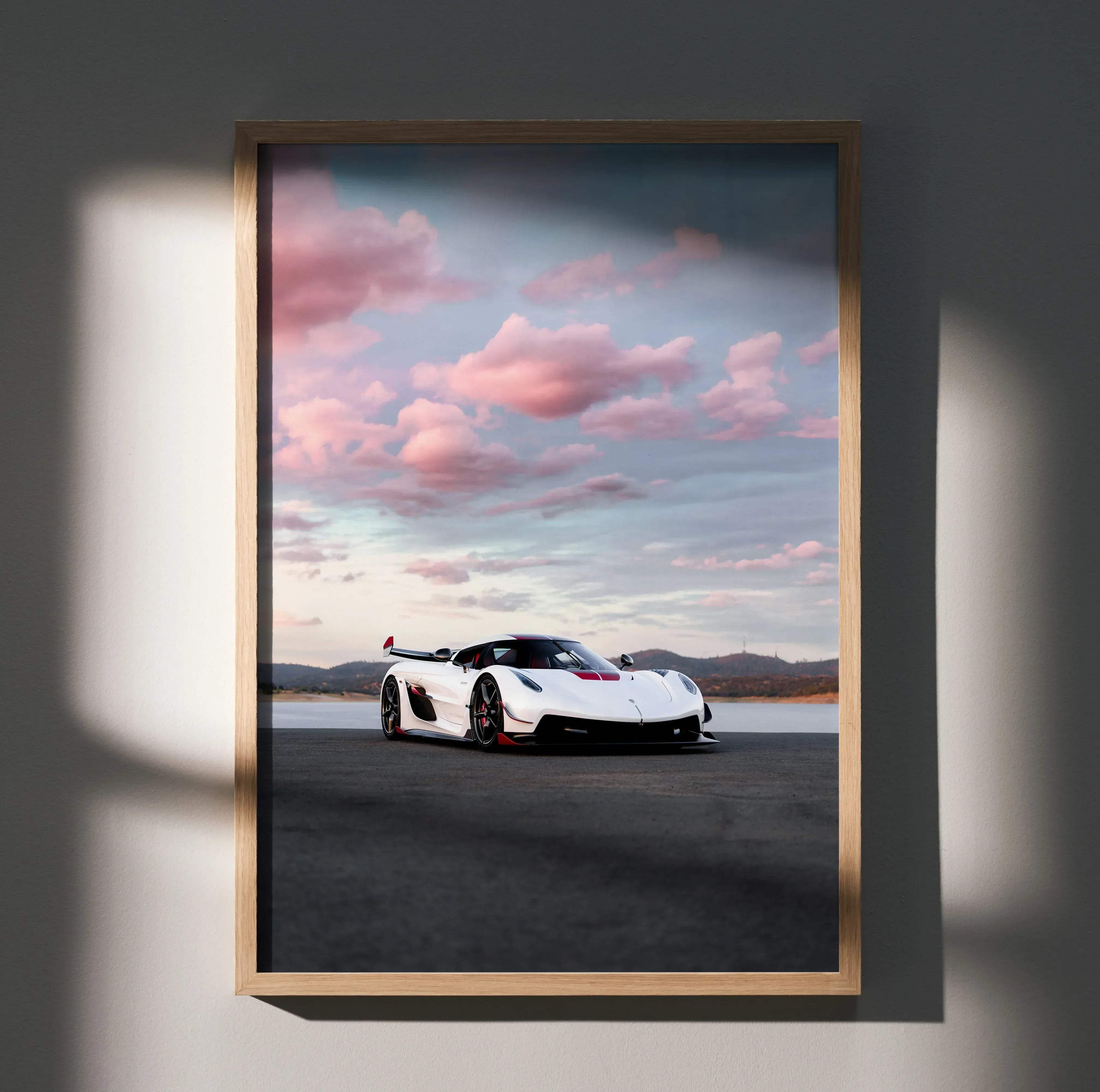 A framed high resolution poster of a white Koenigsegg Jesko hypercar with red accents against pink and gray clouds