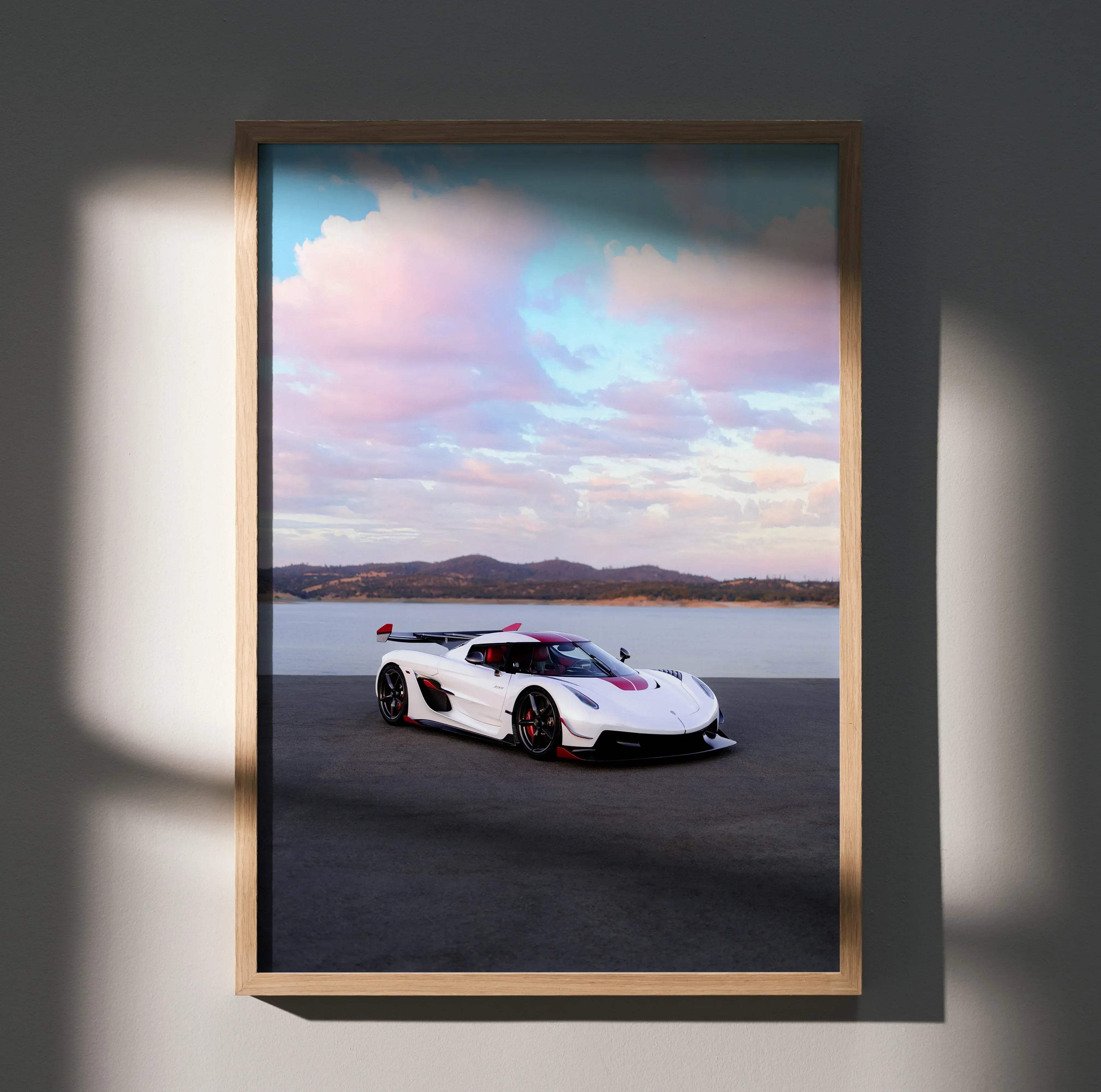 A framed high resolution koenigsegg jesko car poster featuring a white and red hypercar by a lakeside under a pastel sky