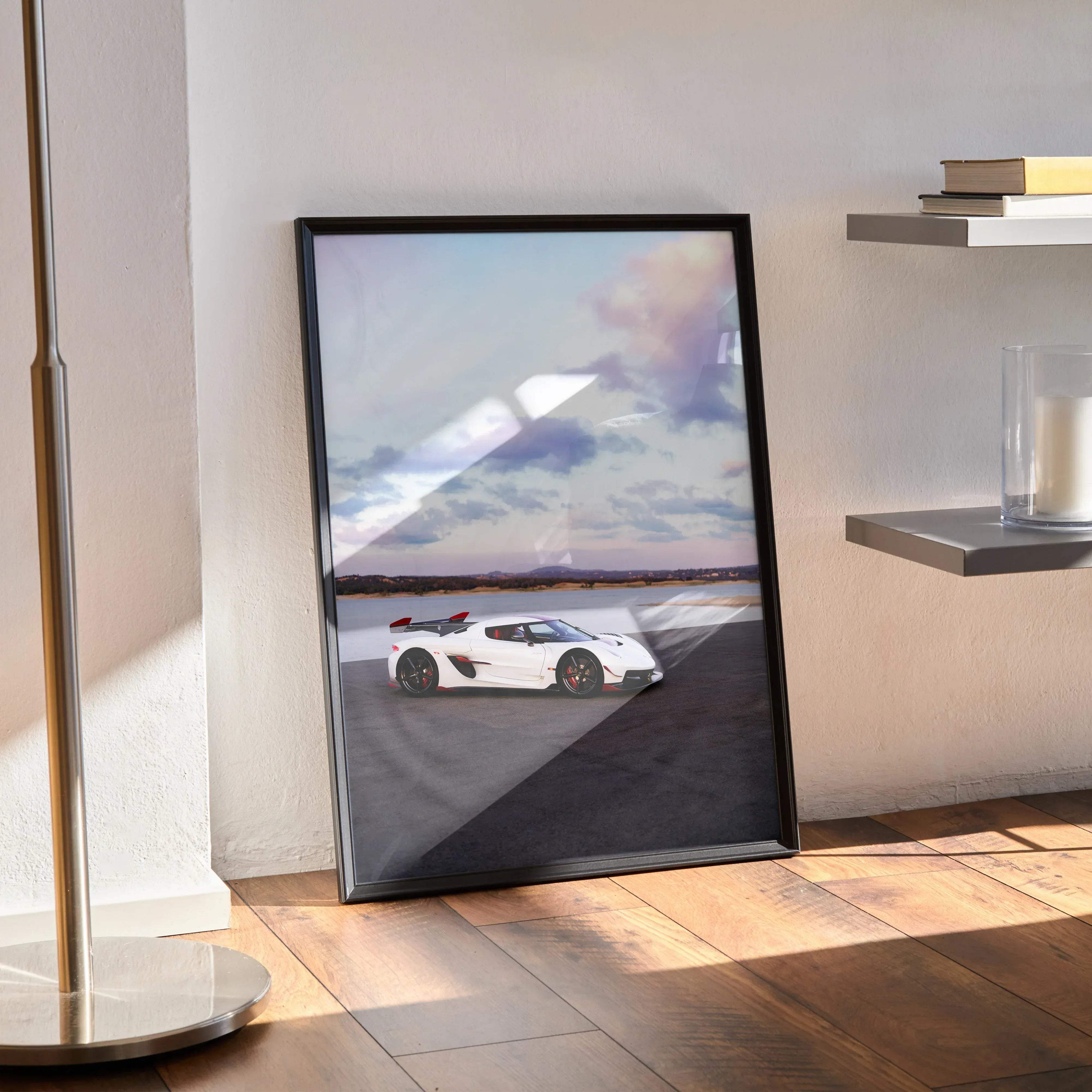 Black-framed poster of a white koenigsegg jesko sports car with red accents on a track under a cloudy sky