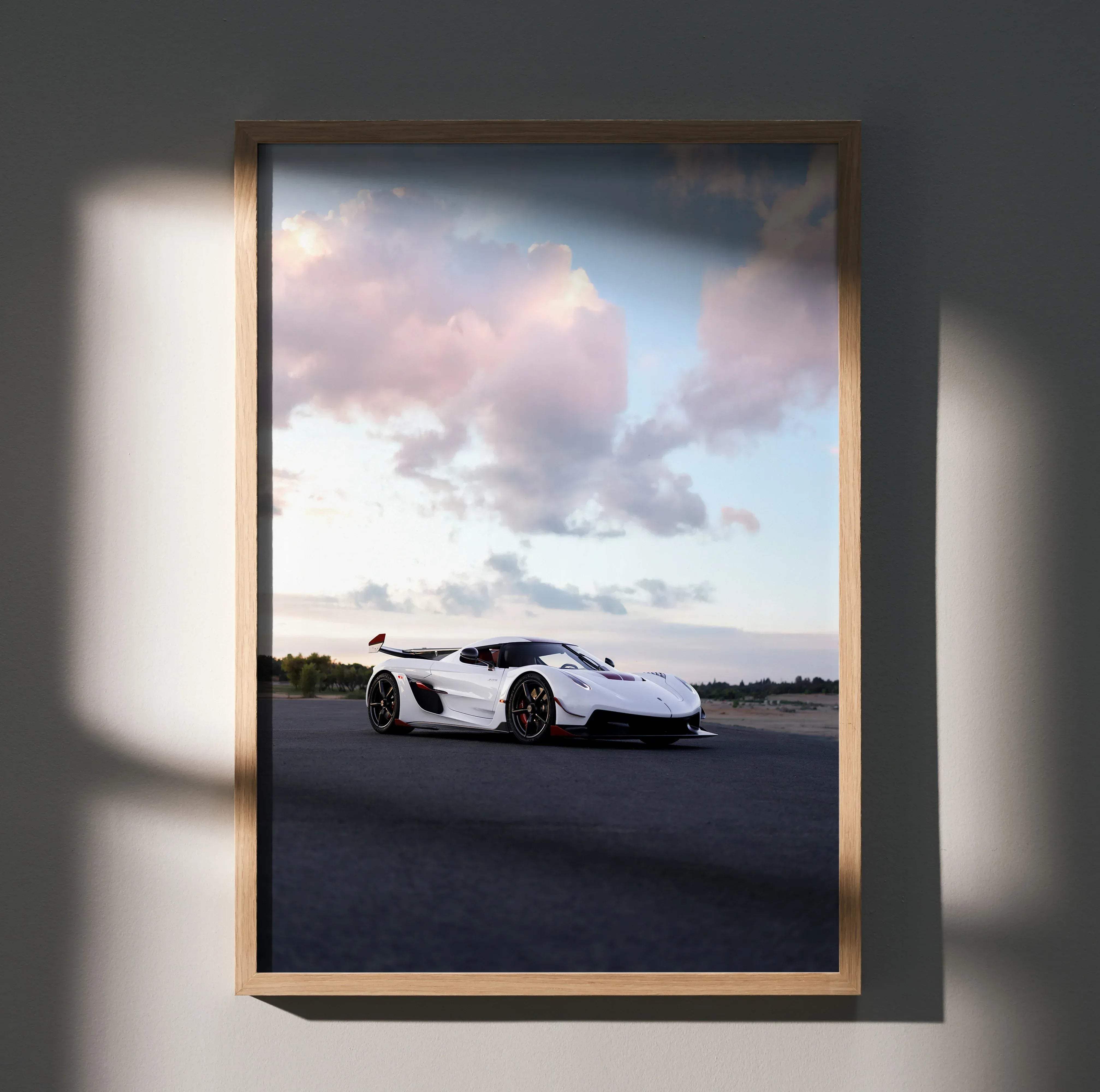 A framed photograph poster of a white koenigsegg jesko hypercar with red accents under a dramatic sky