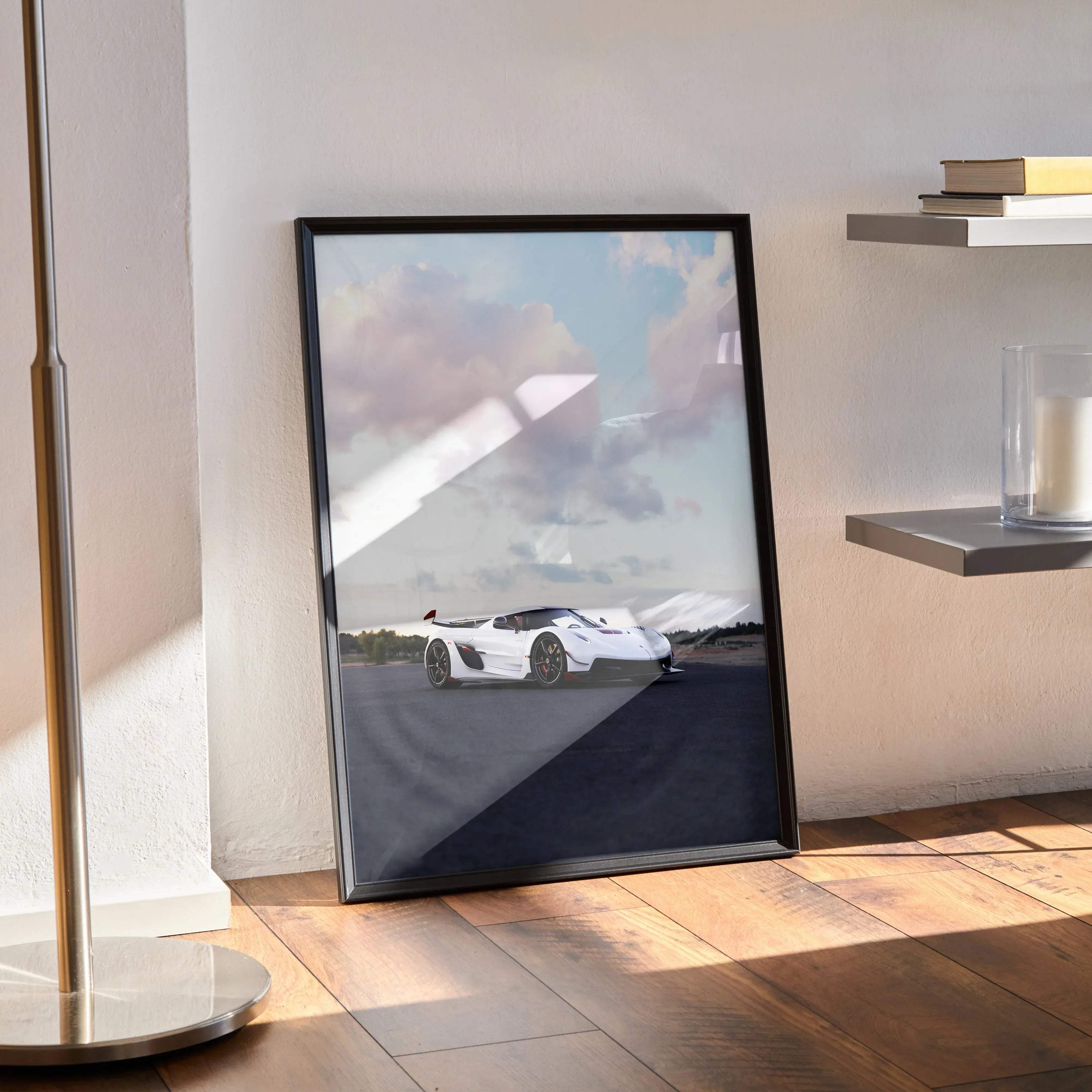 Black-framed poster of a white koenigsegg jesko hypercar speeding on a track under a cloudy sky high resolution