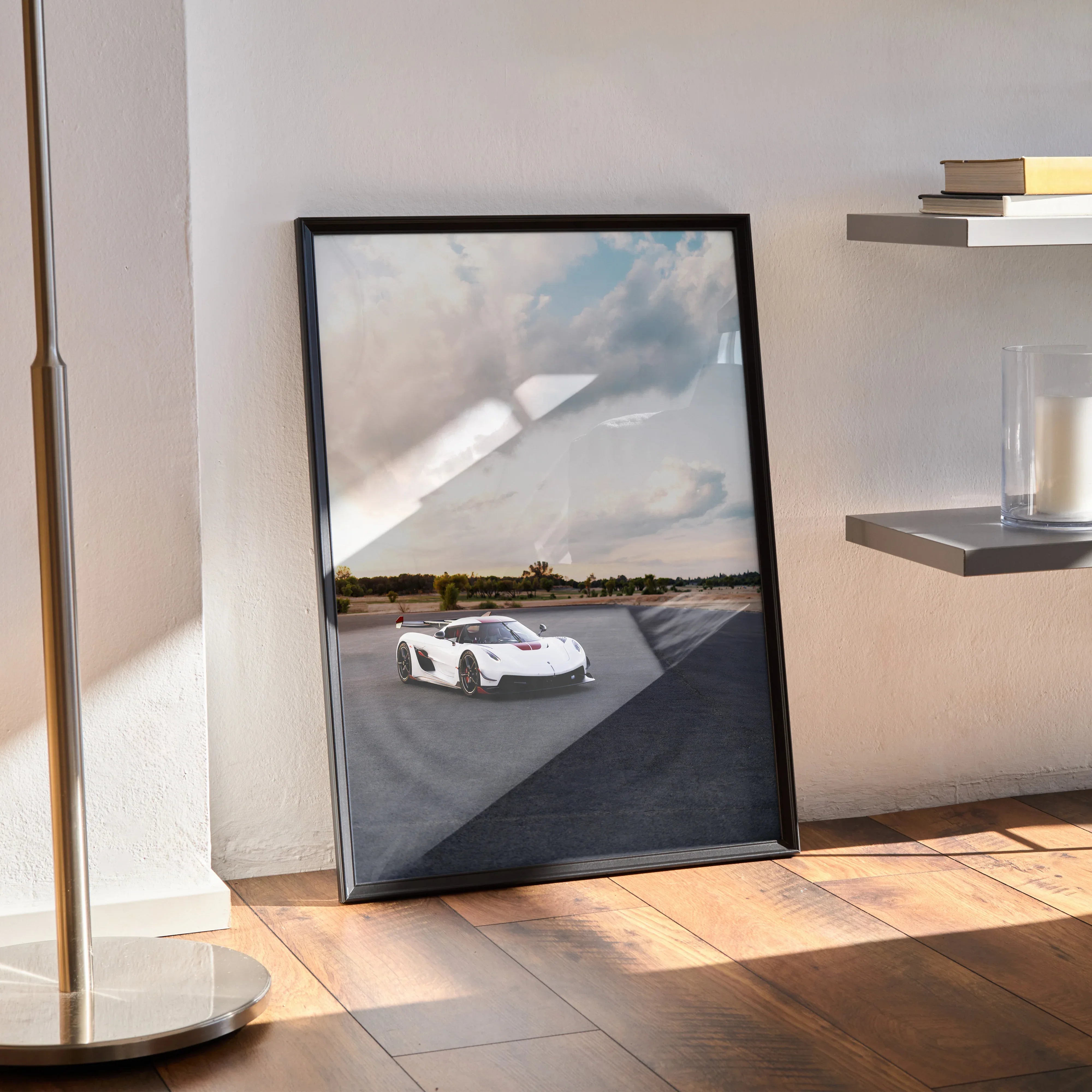 Koenigsegg Jesko poster wall art featuring a white sports car on a racetrack under a cloudy sky in a black frame.