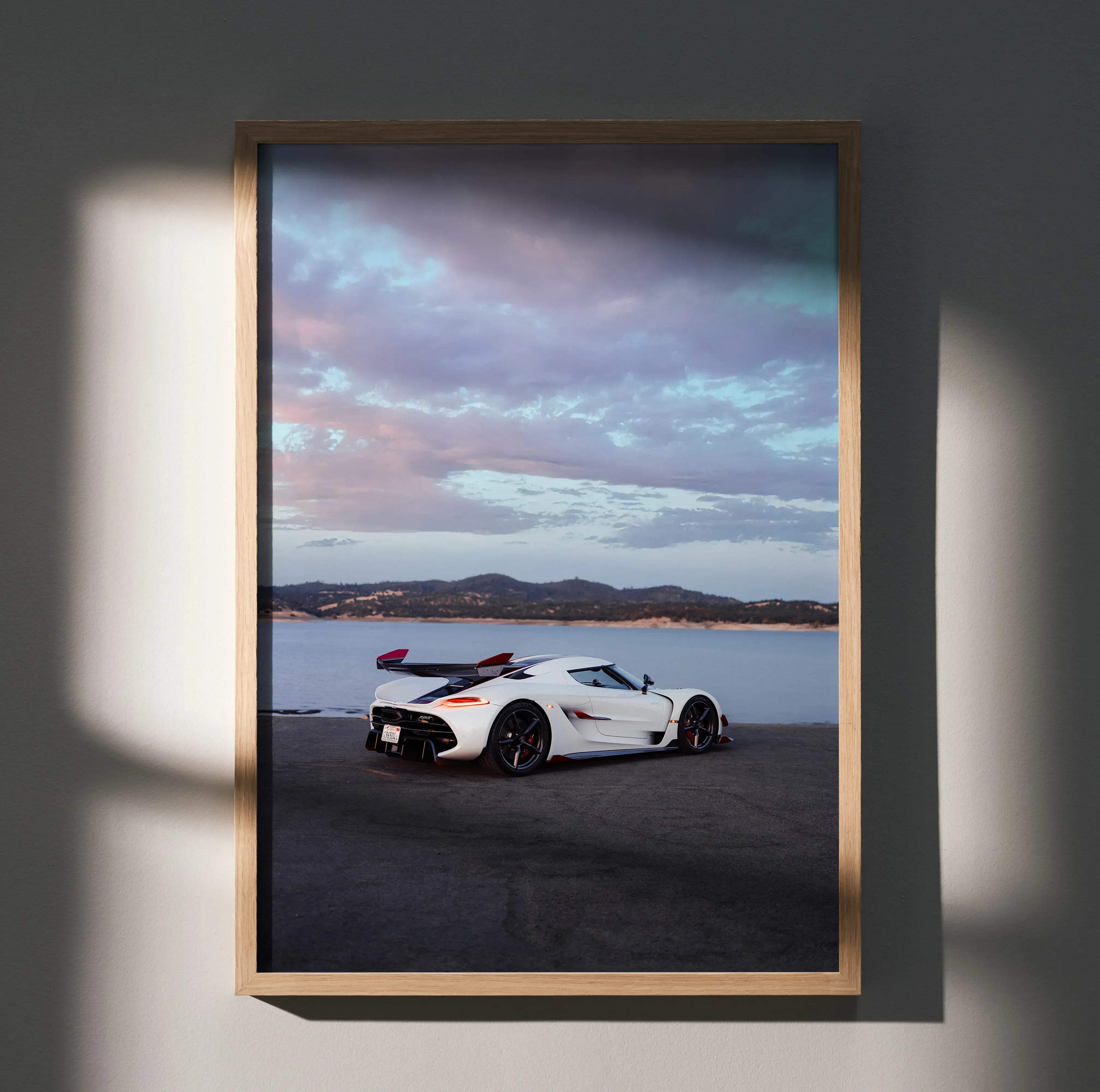A framed Koenigsegg Jesko high resolution car poster featuring a white hypercar with black and red accents near water