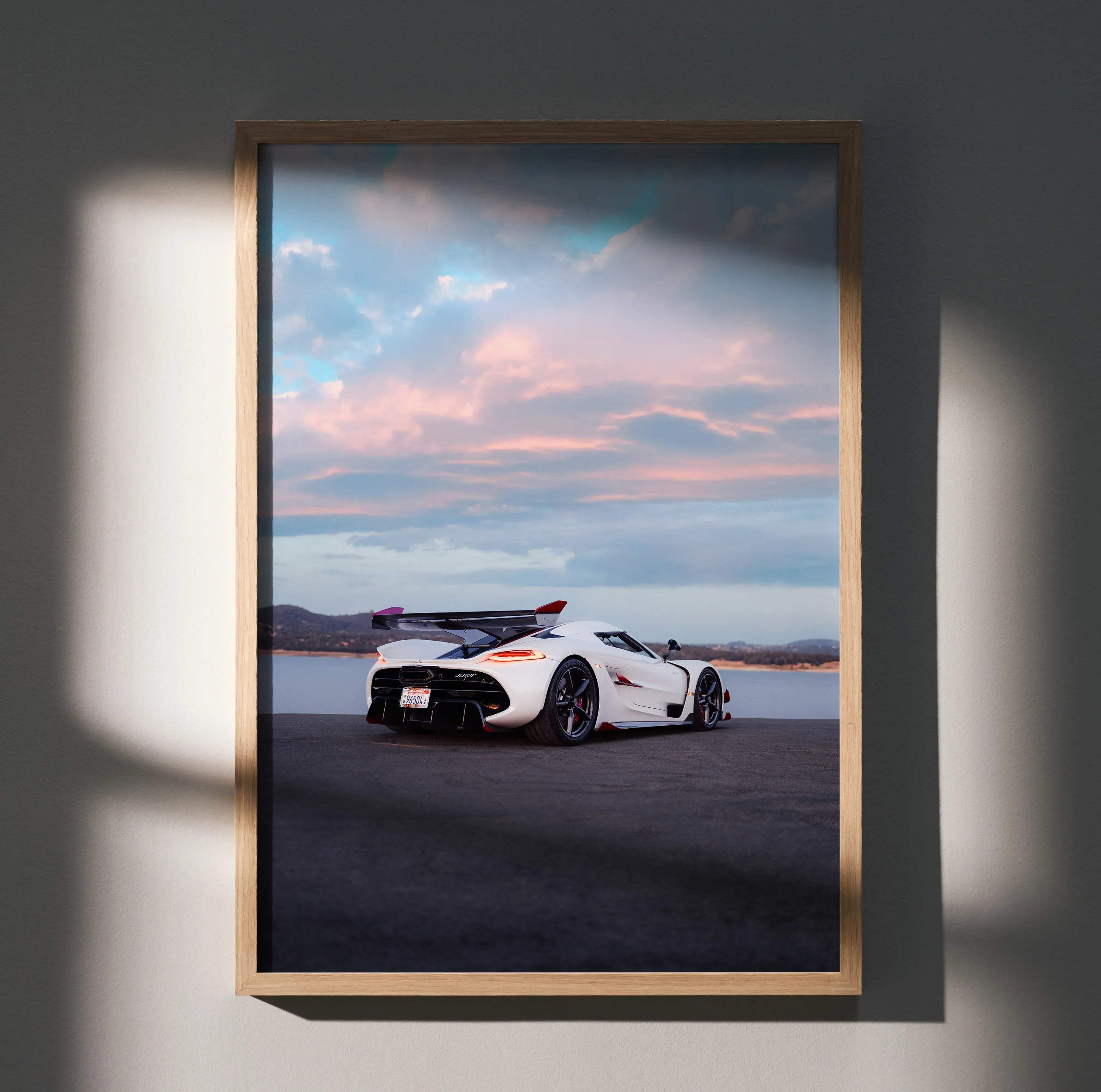 A framed photograph of a white Koenigsegg Jesko hypercar with black and red accents against a dusk sky poster